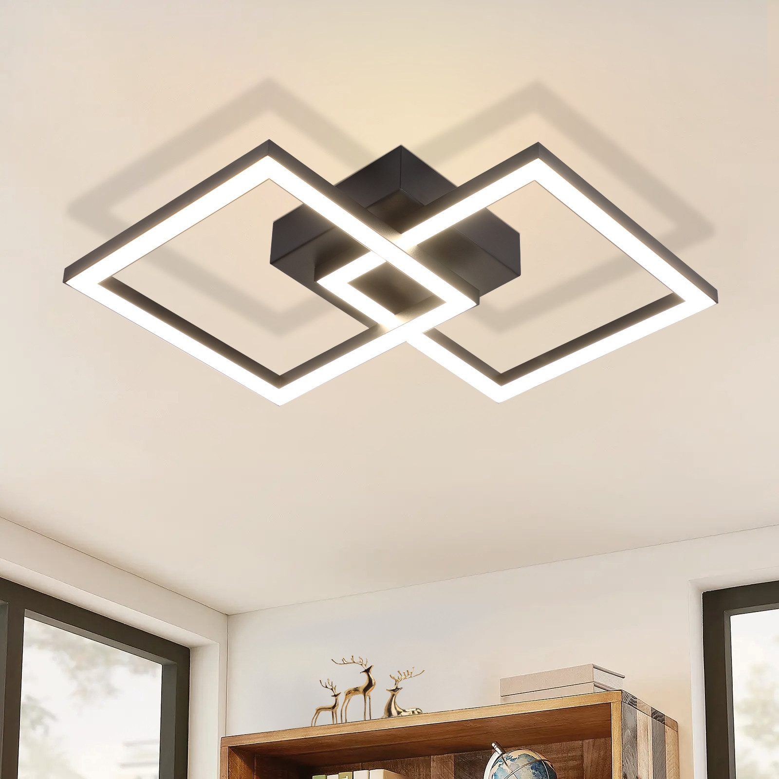 Una moderna plafoniera con quadrati intersecanti è montata su un soffitto bianco in una stanza luminosa.