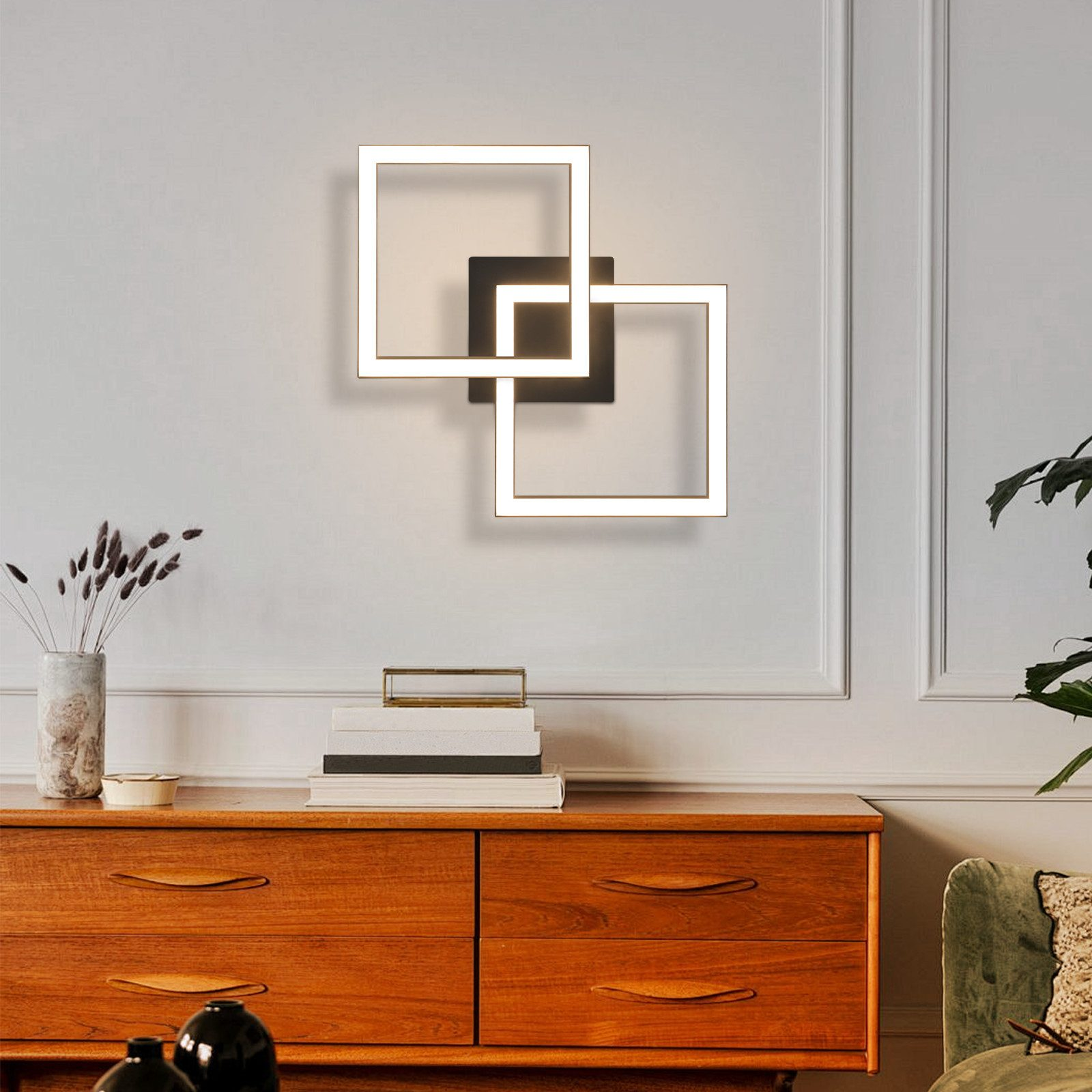Un apparecchio di illuminazione con quadrati che si intersecano è montato sulla parete sopra un comò.