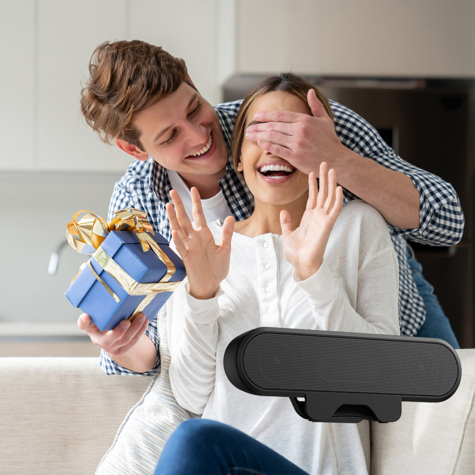 Eine schwarze rechteckige Webcam befindet sich im Vordergrund, während ein Mann einer Frau ein Geschenk macht.