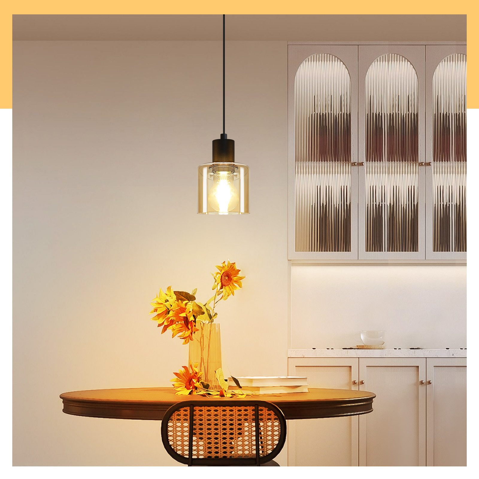 Sala da pranzo con lampada a sospensione in vetro sopra un tavolo rotondo in legno, circondato da sedie e credenza.