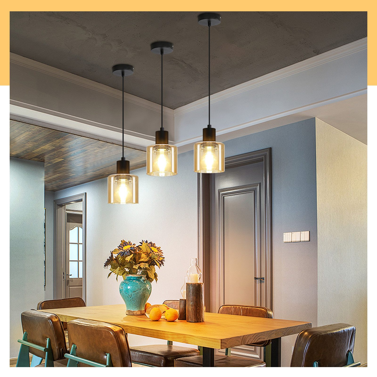 Una zona pranzo presenta lampade a sospensione sopra un tavolo in legno con fiori, piatti e sedie, creando un'atmosfera accogliente.