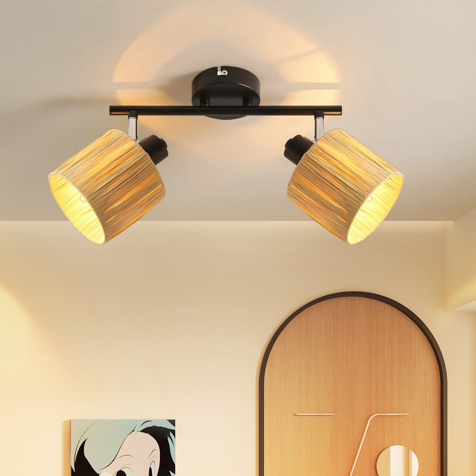 Due lampade ricoperte di paglia sono posizionate su un supporto nero contro una parete bianca con un pannello decorativo.
