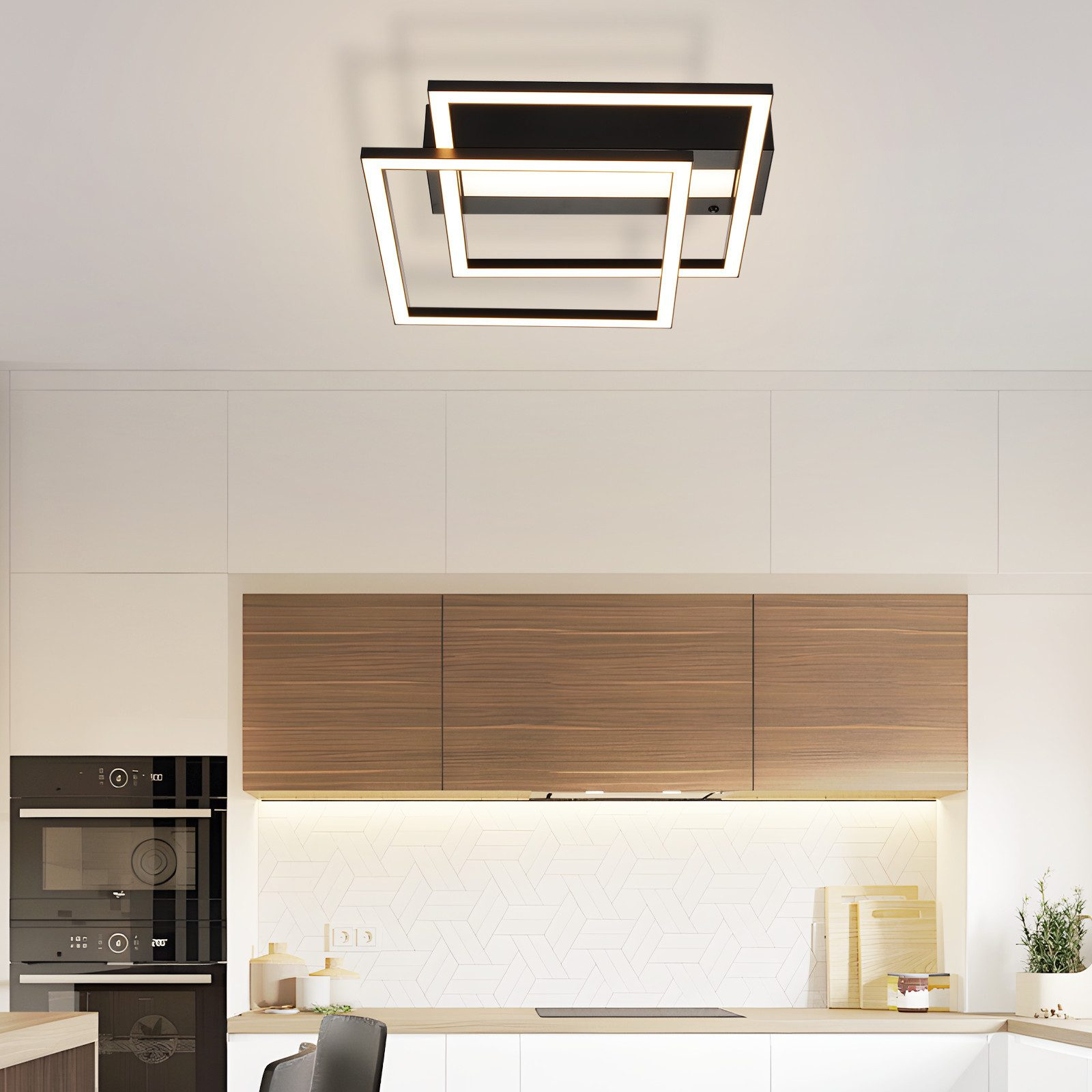 Una scena di cucina presenta una plafoniera nera con cornici LED quadrate sopra mobili in legno e ripiani bianchi.