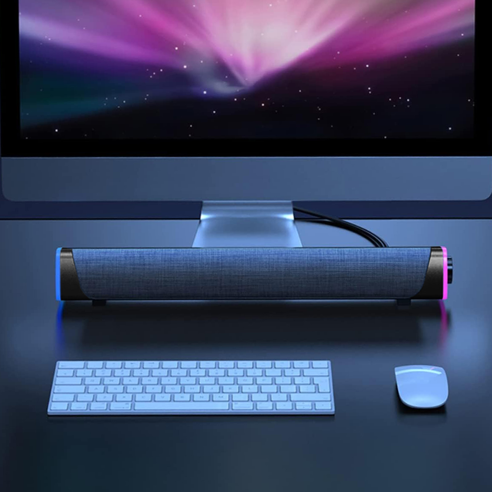 Eine Soundbar befindet sich unterhalb eines Computermonitors, mit einer Tastatur und Maus in der Nähe auf einem Schreibtisch.