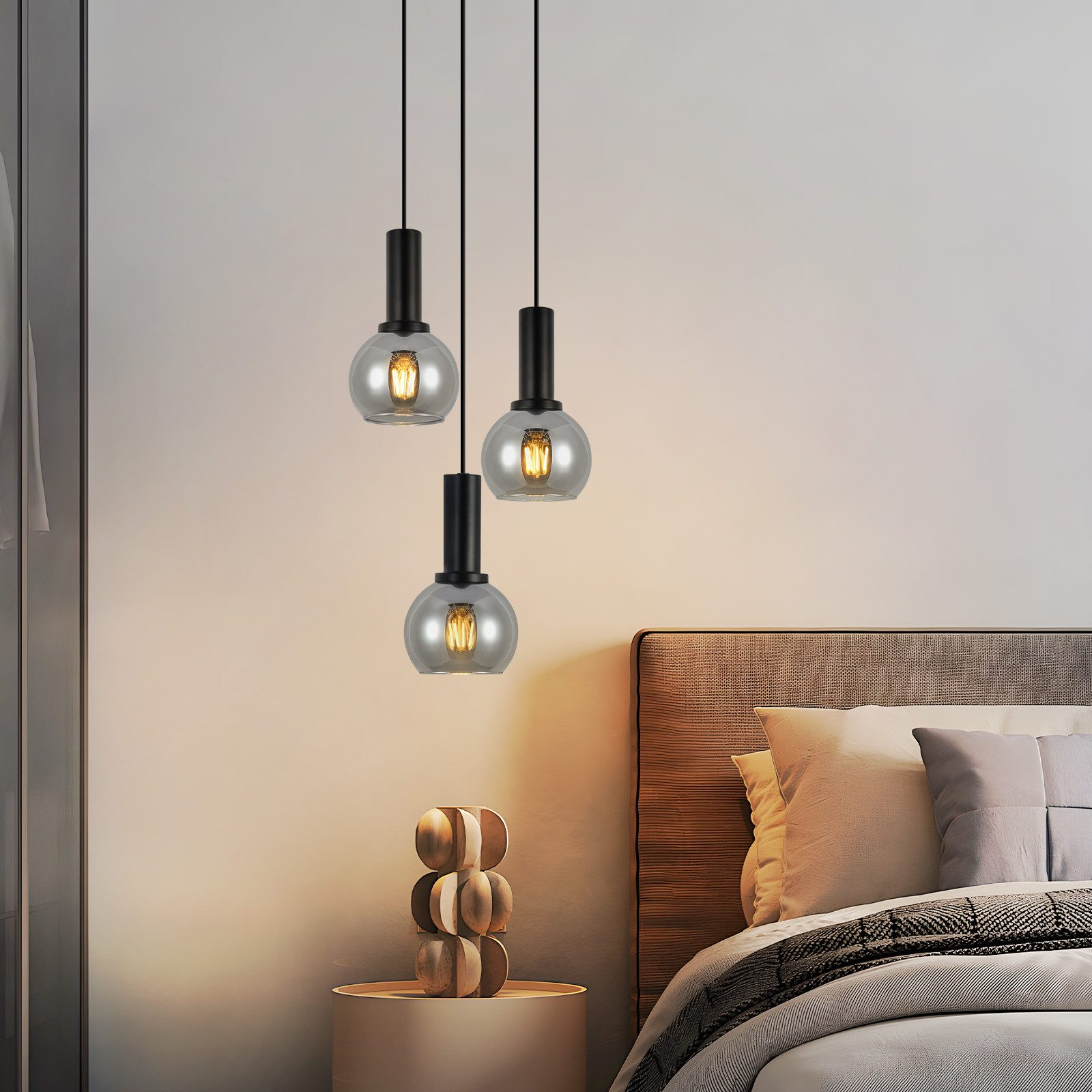 Trzy lampy wiszące z kloszami z przydymionego szkła wiszące w sypialni, prezentujące nowoczesne oświetlenie i wystrój wnętrz.