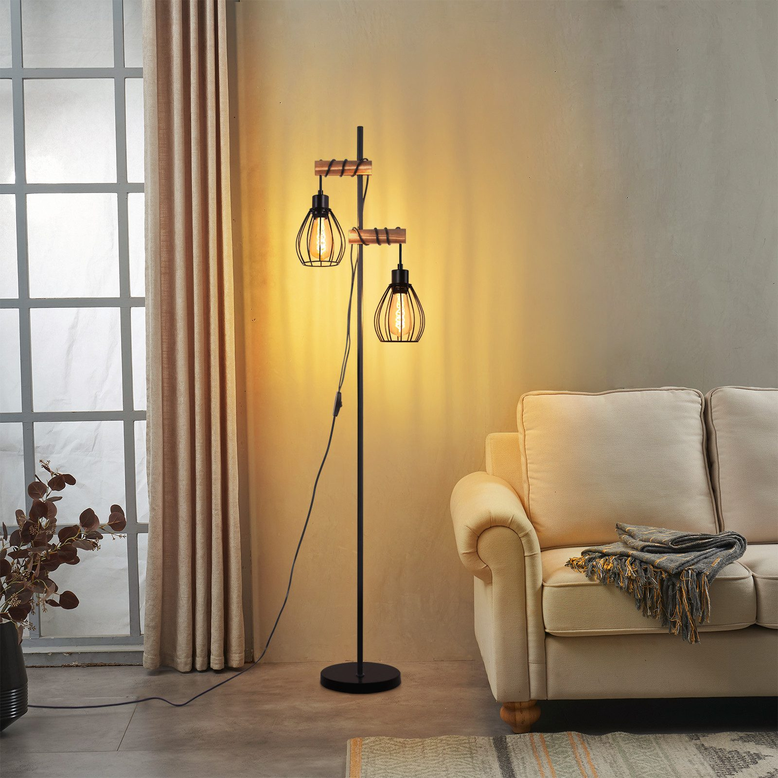 Una lampada da terra con due luci ingabbiate si trova accanto a un divano color crema e a una finestra con tende.