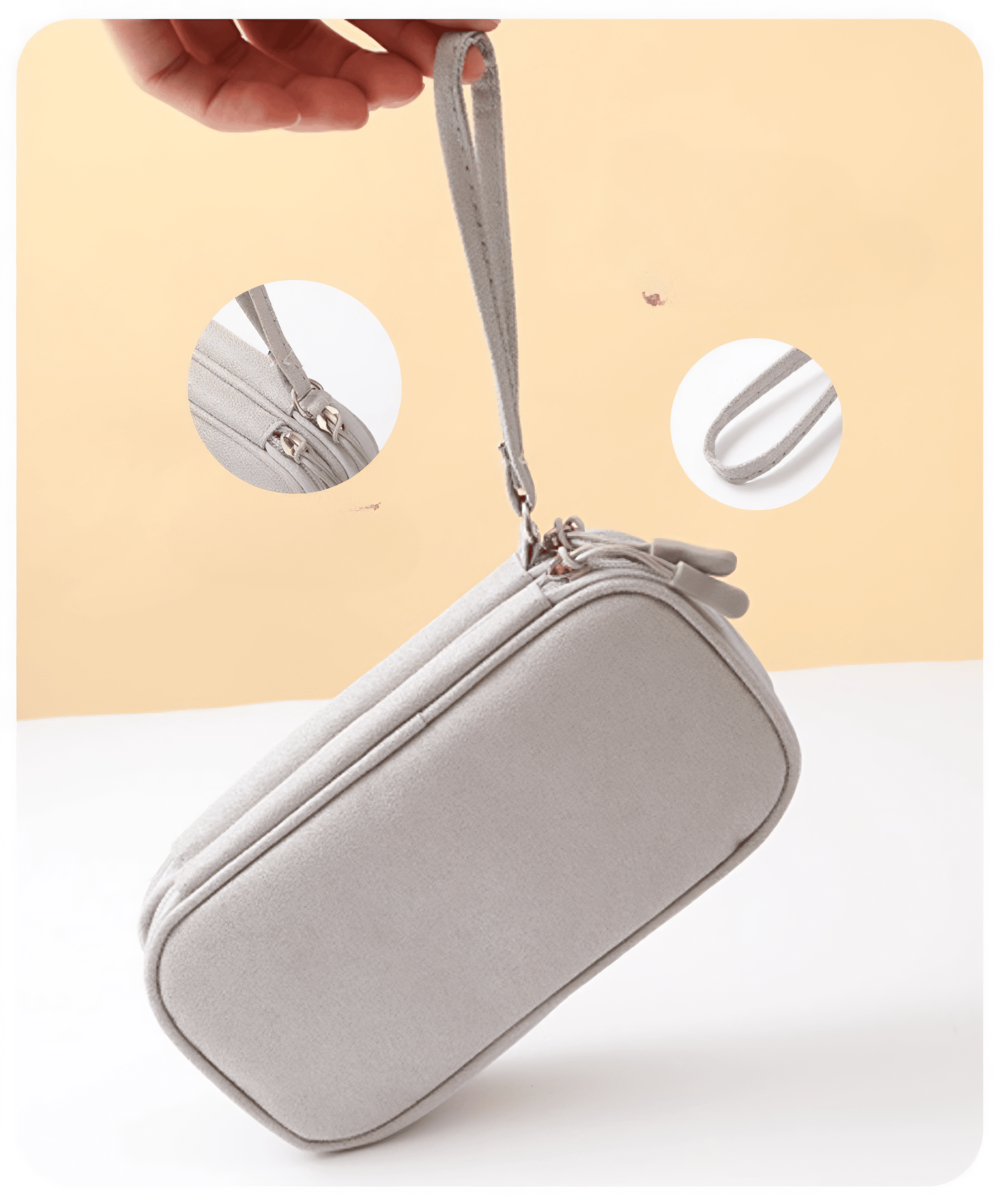 Eine graue Tasche mit doppeltem Reißverschluss und Handschlaufe wird vor einem abgestuften beigen und weißen Hintergrund gehalten.