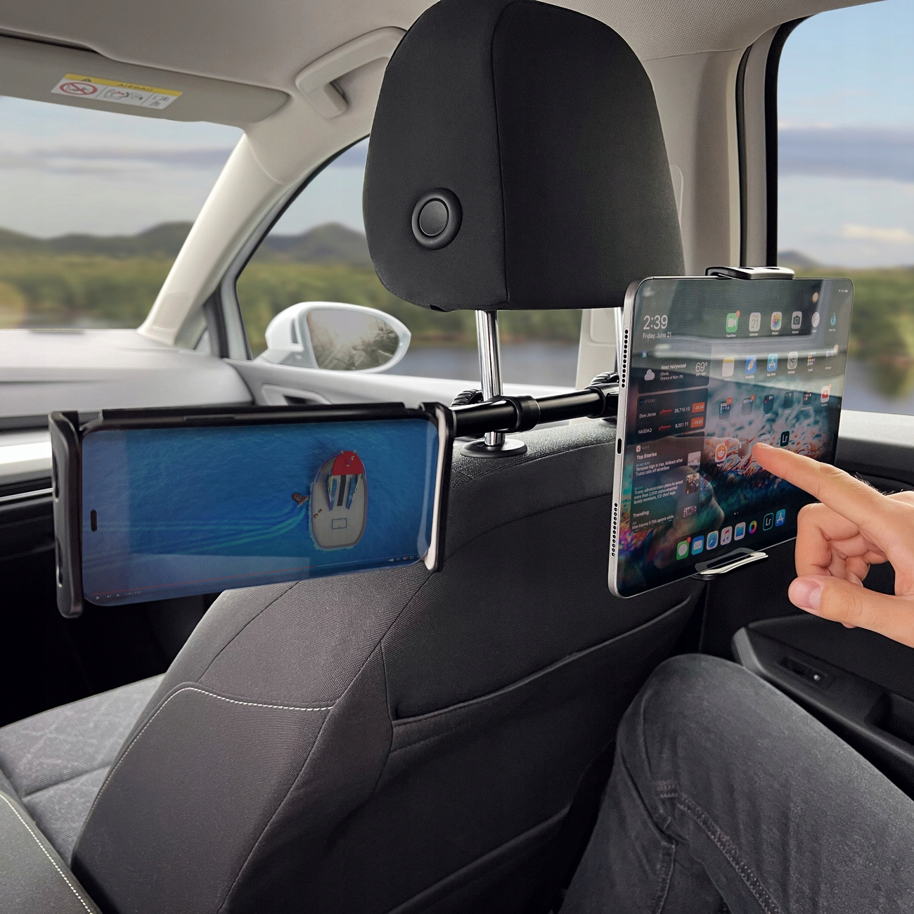 Tablet i telefon są zamontowane na zagłówku samochodowym. Osoba dotyka ekranu tabletu.