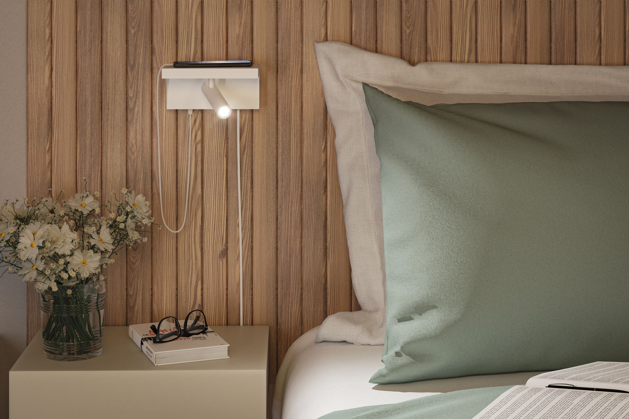 Ein Nachttisch mit Lampe, Buch, Brille und Blumen in einer Schlafzimmerumgebung.