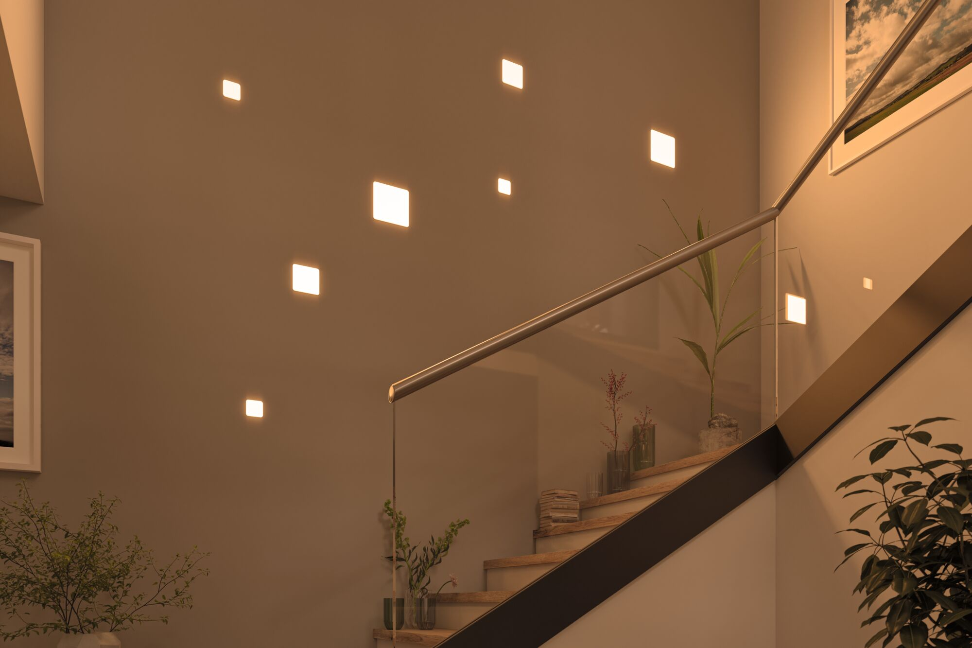 Innenansicht einer Treppe mit Glasgeländer, Pflanzen und eingelassenen Leuchten an der Wand.