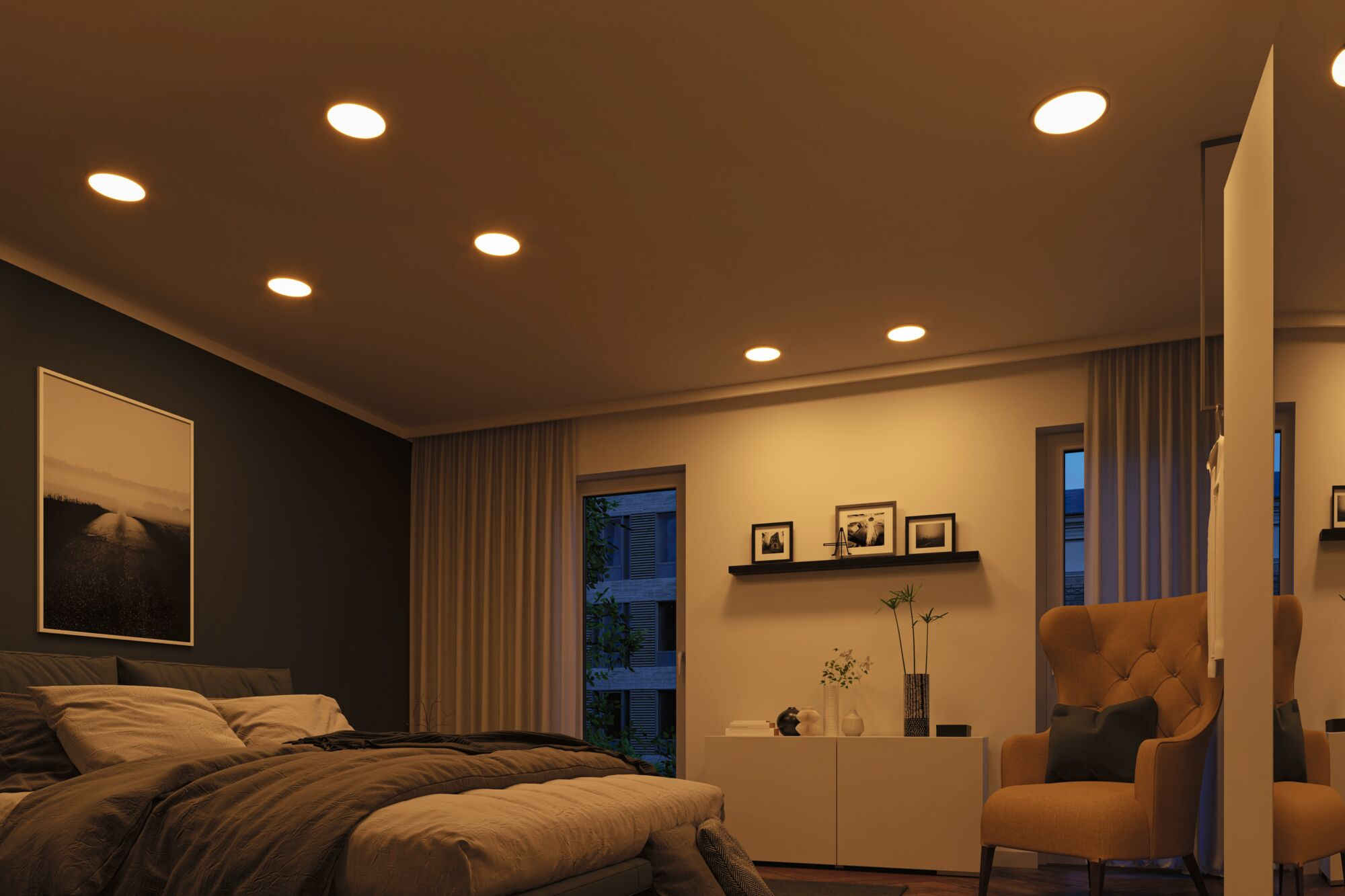 Schlafzimmer, beleuchtet von Einbaudeckenleuchten. Das Zimmer hat ein Bett, einen Schrank und ein großes Fenster.