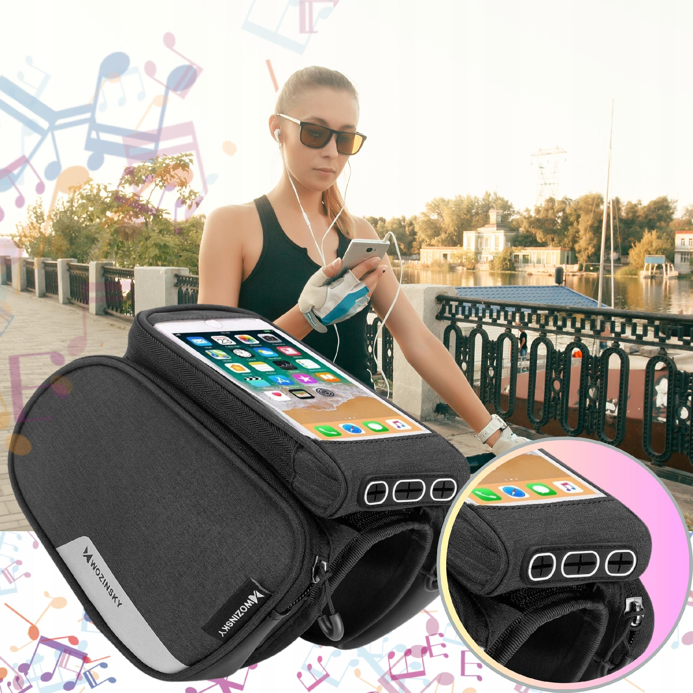 Kobieta korzysta ze smartfona w torbie na kierownicę na rowerze z jeziorem w tle, nosi okulary przeciwsłoneczne.