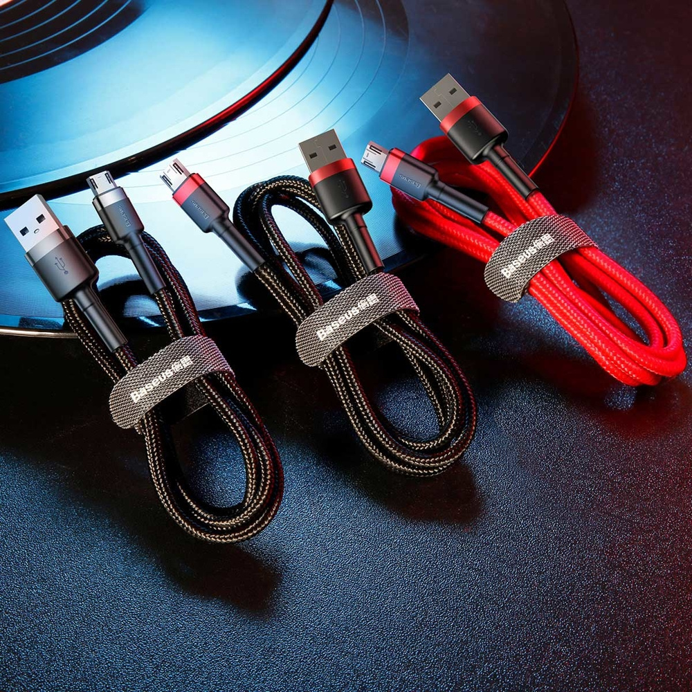 Trzy kable USB z różnymi złączami, owinięte paskami, na powierzchni. Jeden czerwony, inne czarne.