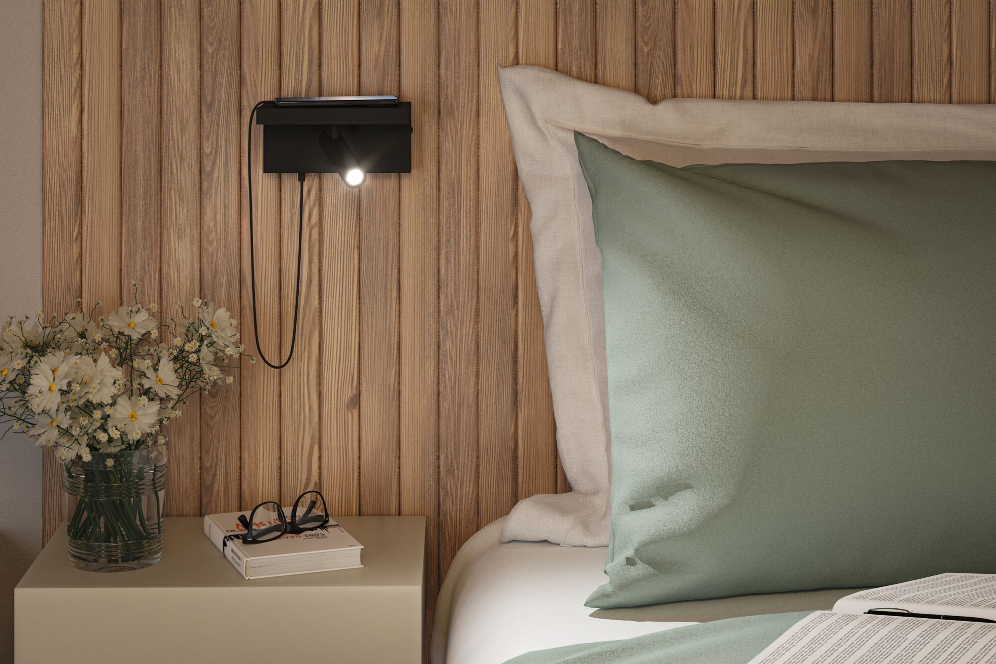 Une scène de chevet avec une lampe murale, des fleurs, un livre avec des lunettes et un lit partiellement visible.