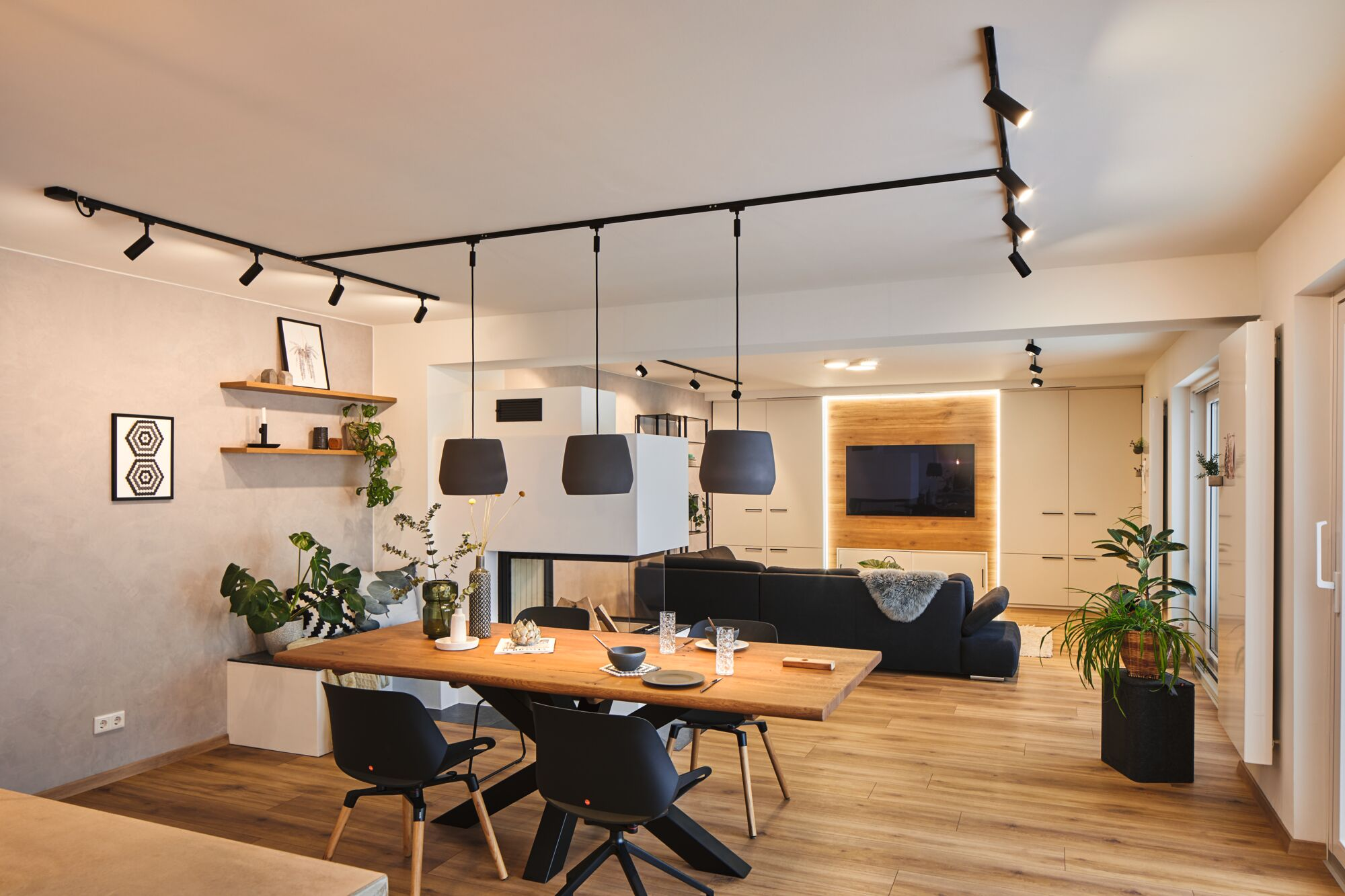 Dobrze oświetlona jadalnia z oświetleniem szynowym, drewnianym stołem i nowoczesnym wystrojem.