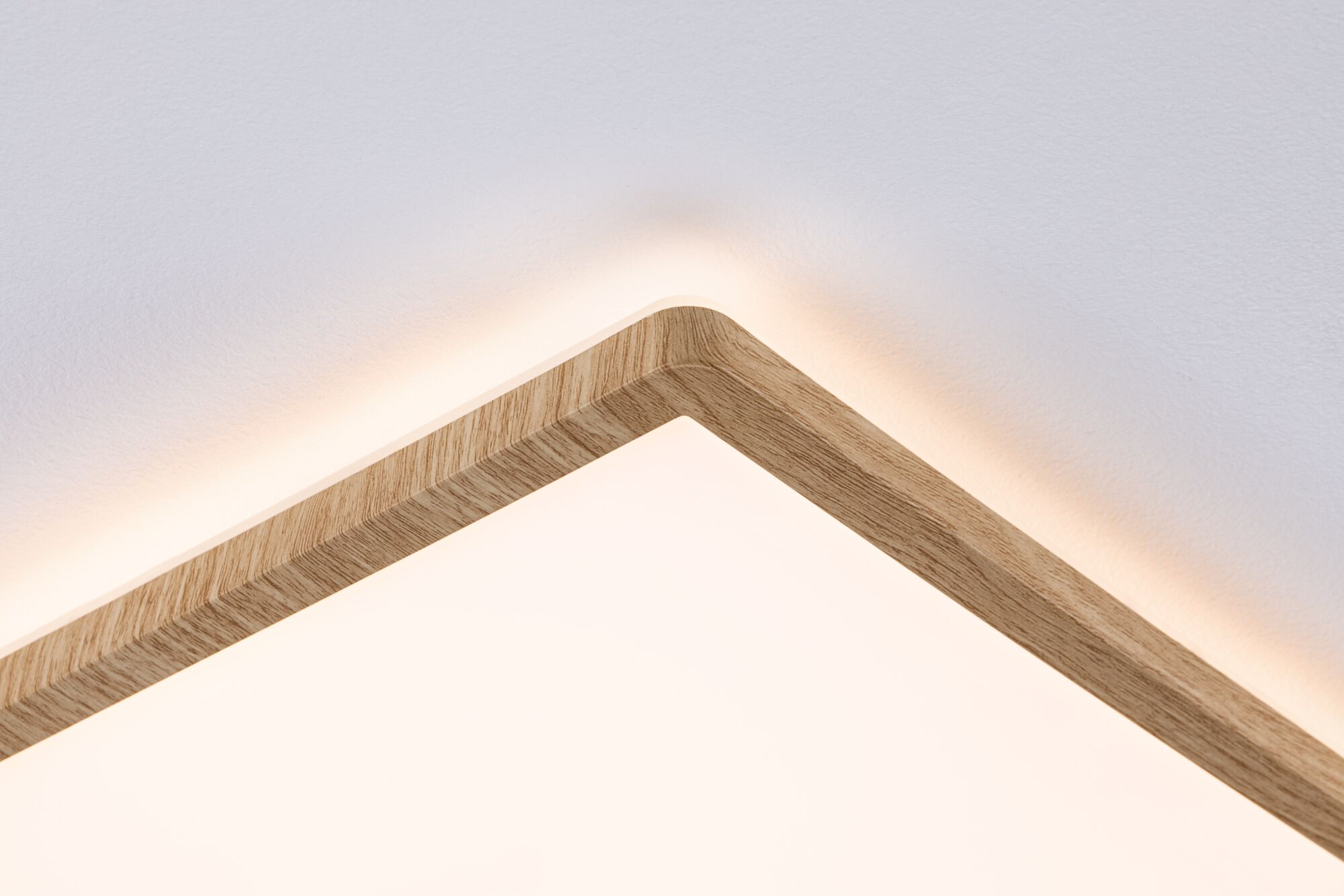 Zbliżenie kwadratowej oprawy oświetleniowej z drewnianą ramą i białym środkiem, zamontowanej na białym suficie.