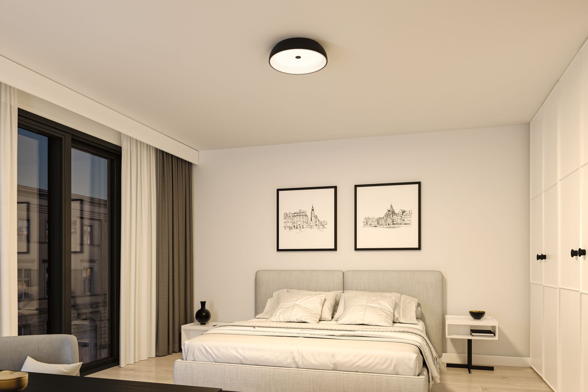 Sypialnia z łóżkiem, dwoma oprawionymi obrazami, oknem i czarną oprawą oświetleniową sufitową.