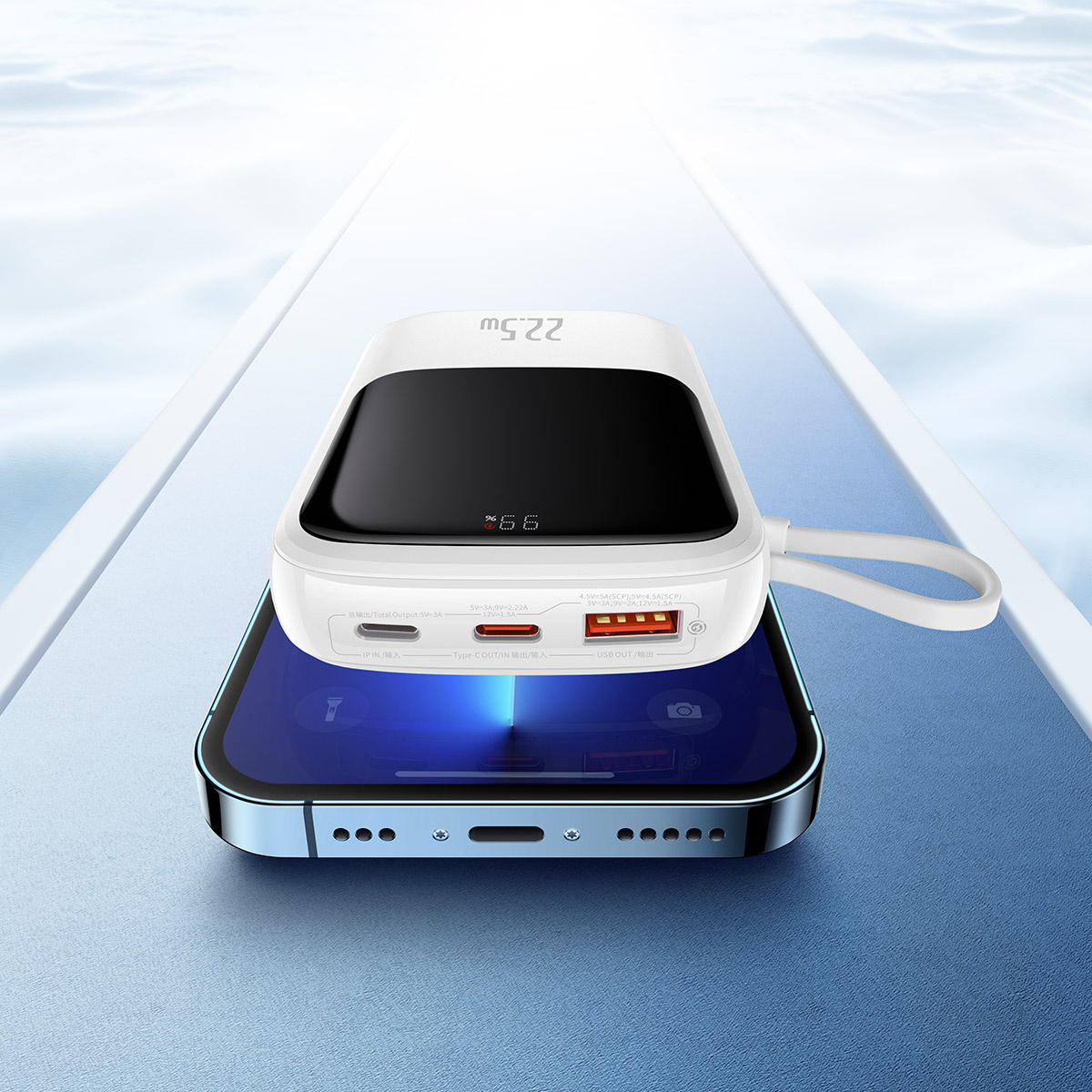 Biały power bank na niebieskim telefonie, prezentujący możliwości ładowania.