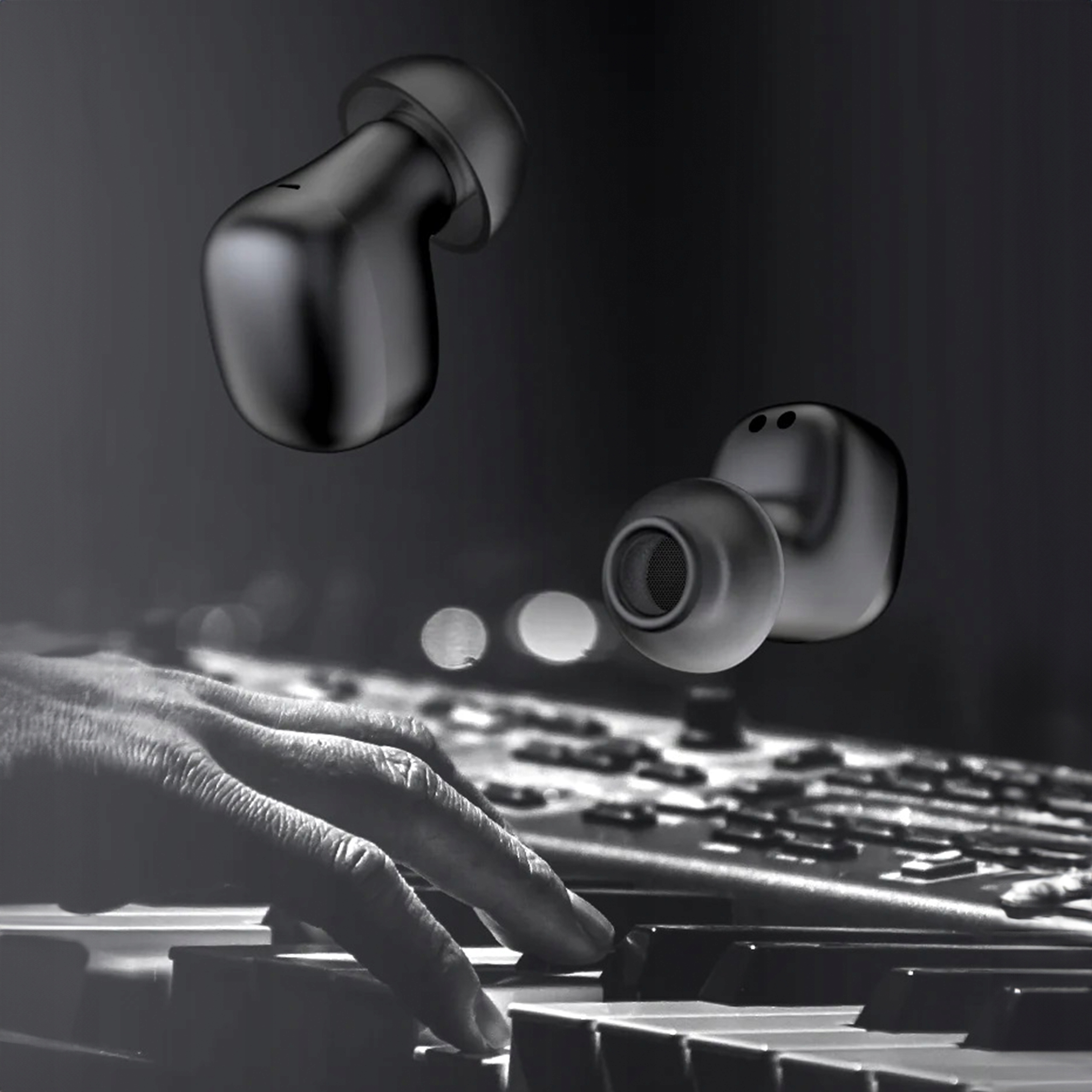 Dwa czarne słuchawki douszne unoszą się nad klawiaturą fortepianu, na której gra ręka osoby.