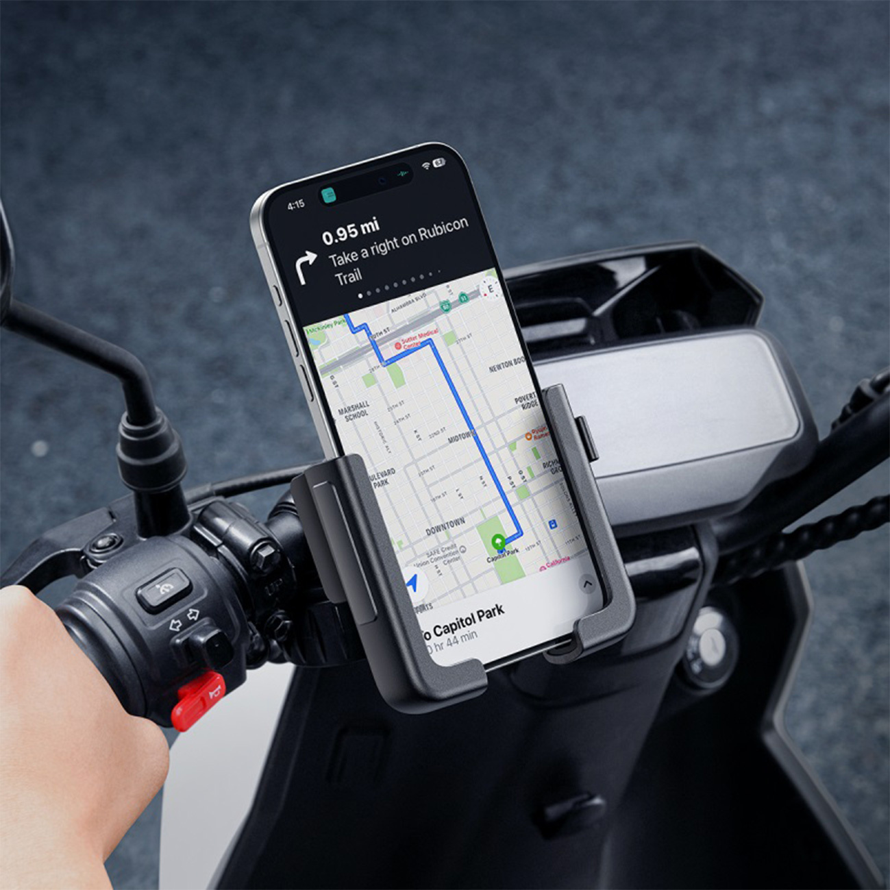 Zdjęcie przedstawia smartfon zamontowany na kierownicy motocykla za pomocą czarnego uchwytu na telefon, wyświetlający mapę do nawigacji.