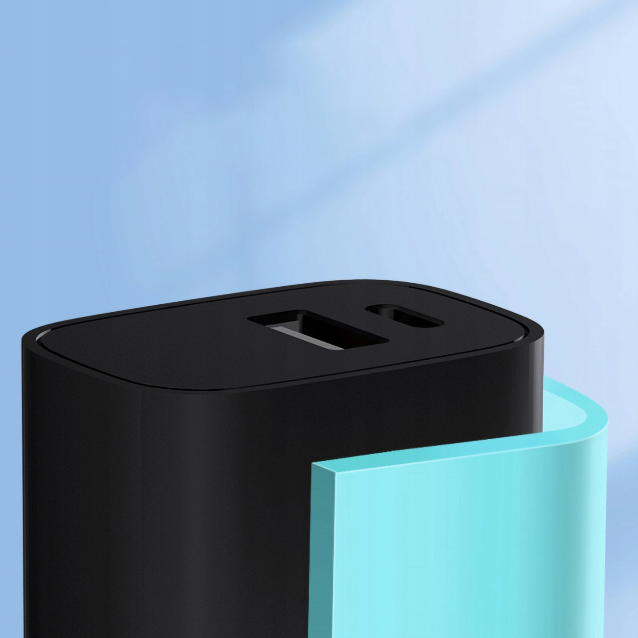 Czarna ładowarka USB z dwoma portami na tle niebieskiego gradientu, w pobliżu jasnoniebieskiej krzywej.