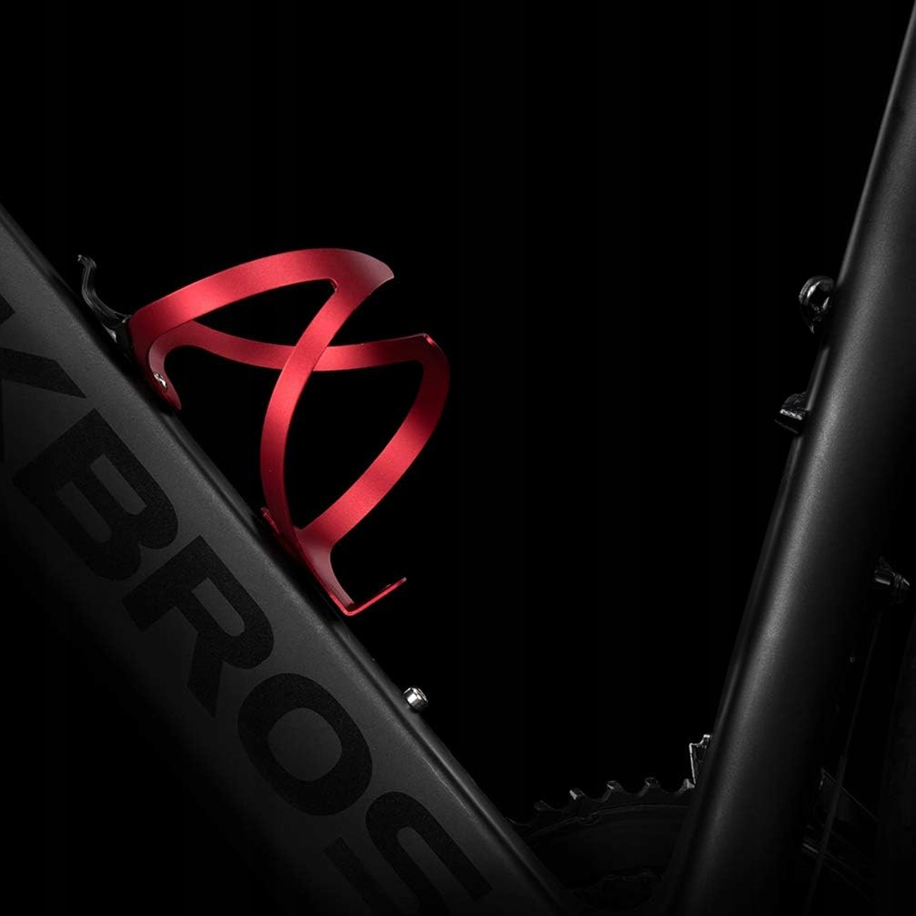 Czerwony uchwyt na bidon rowerowy ROCKBROS zamontowany na czarnej ramie roweru na ciemnym tle.