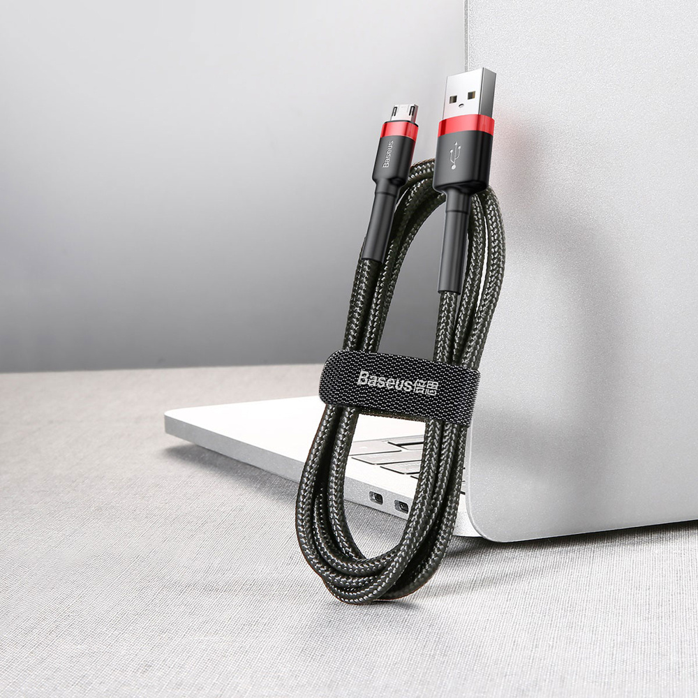 Czarny, pleciony kabel USB z czerwonymi akcentami, zabezpieczony paskiem w pobliżu laptopa.