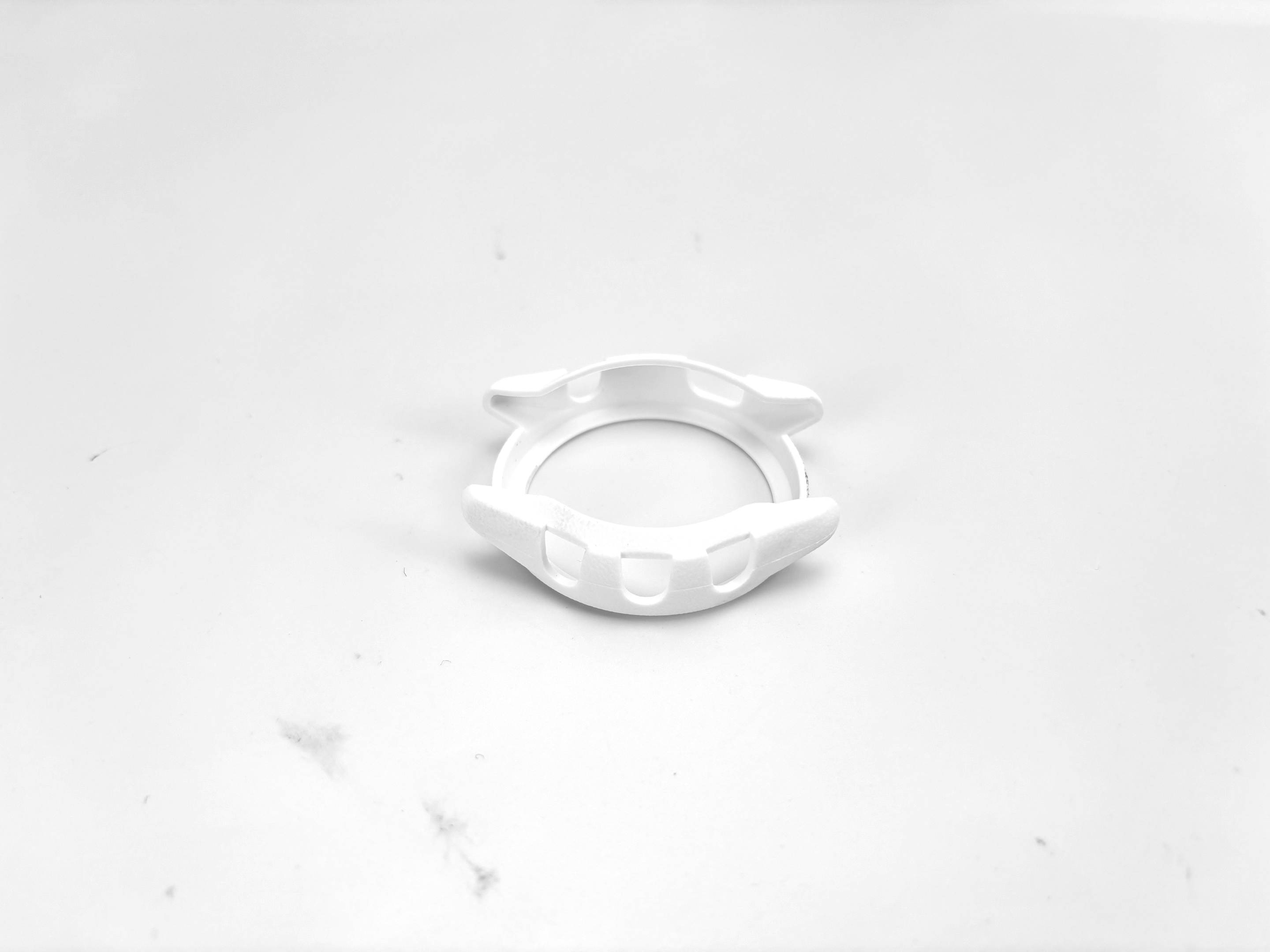 Un protettore per cassa di orologio bianco si trova al centro di uno sfondo bianco, caratterizzato da un design semplice.