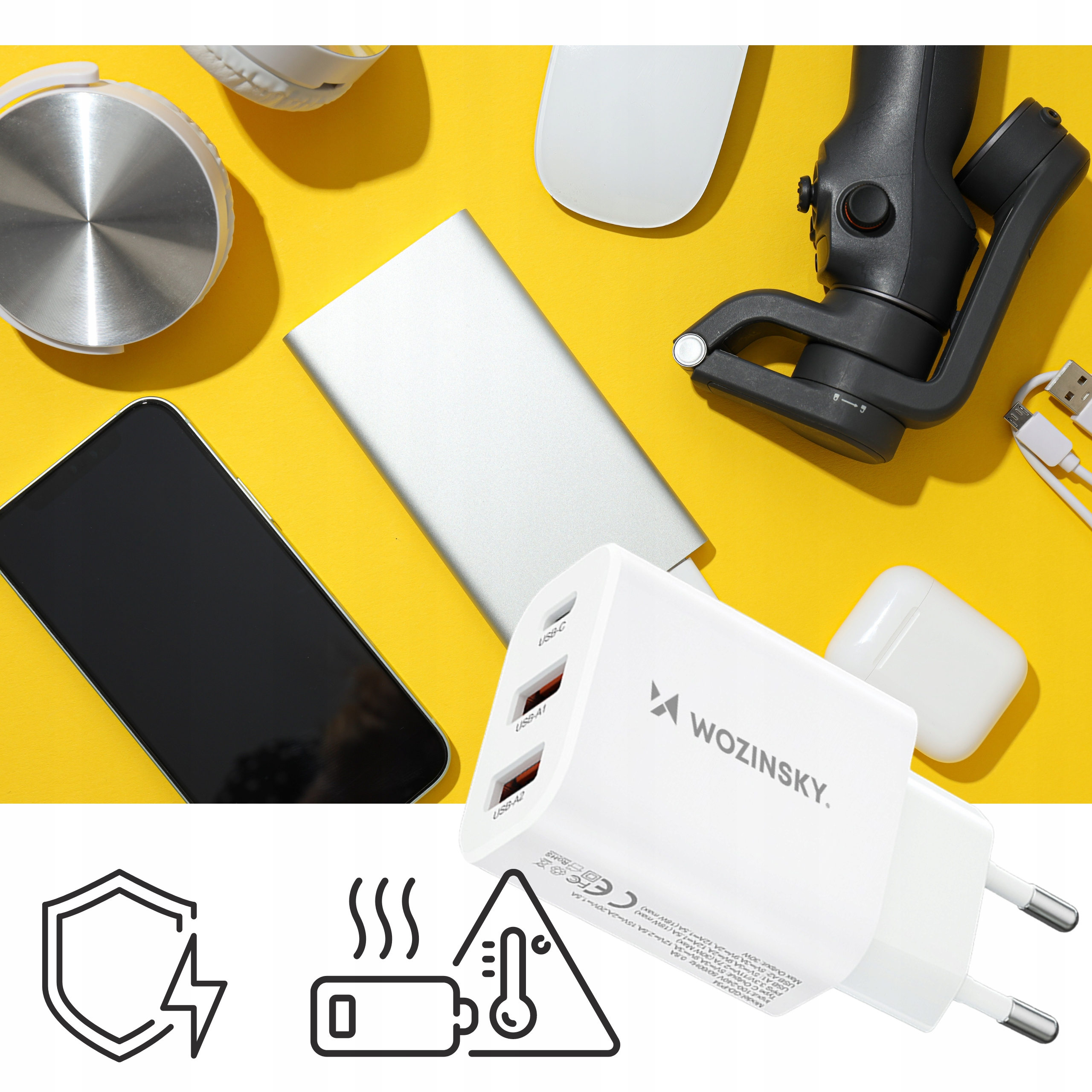 Żółta powierzchnia z telefonem, ładowarką, słuchawkami i innymi gadżetami. Ładowarka Wozinsky jest w centrum.