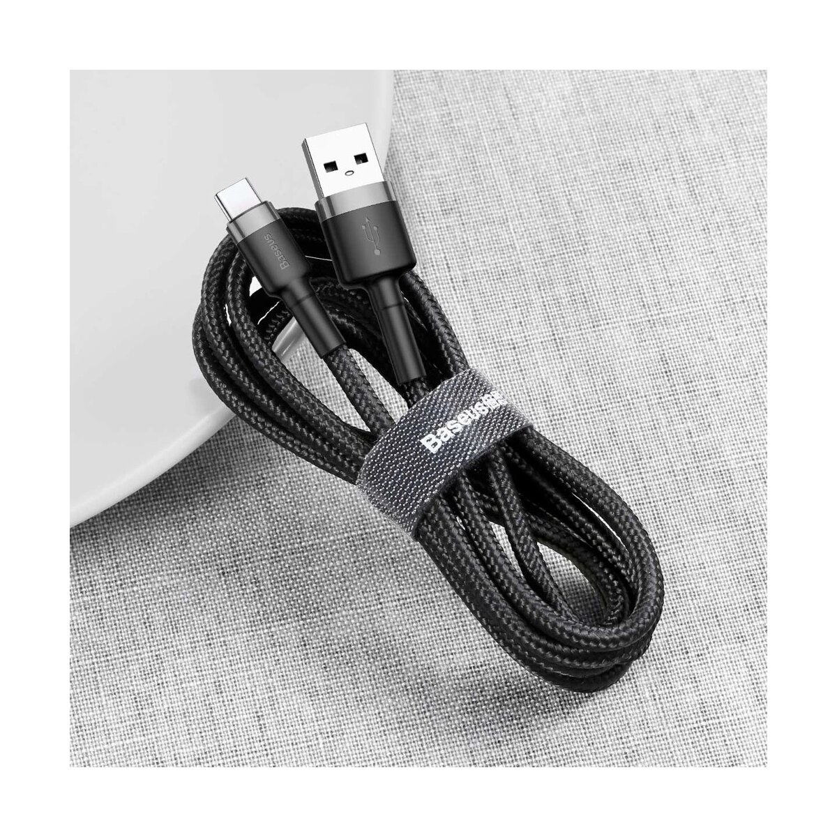Zwarte USB-kabel met USB-C- en USB-A-connectoren, opgerold op een grijs oppervlak.
