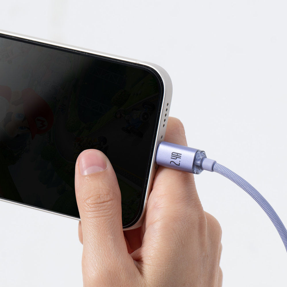 Ręka trzyma telefon z podłączonym fioletowym kablem Baseus, częściowo zasłaniającym ekran.