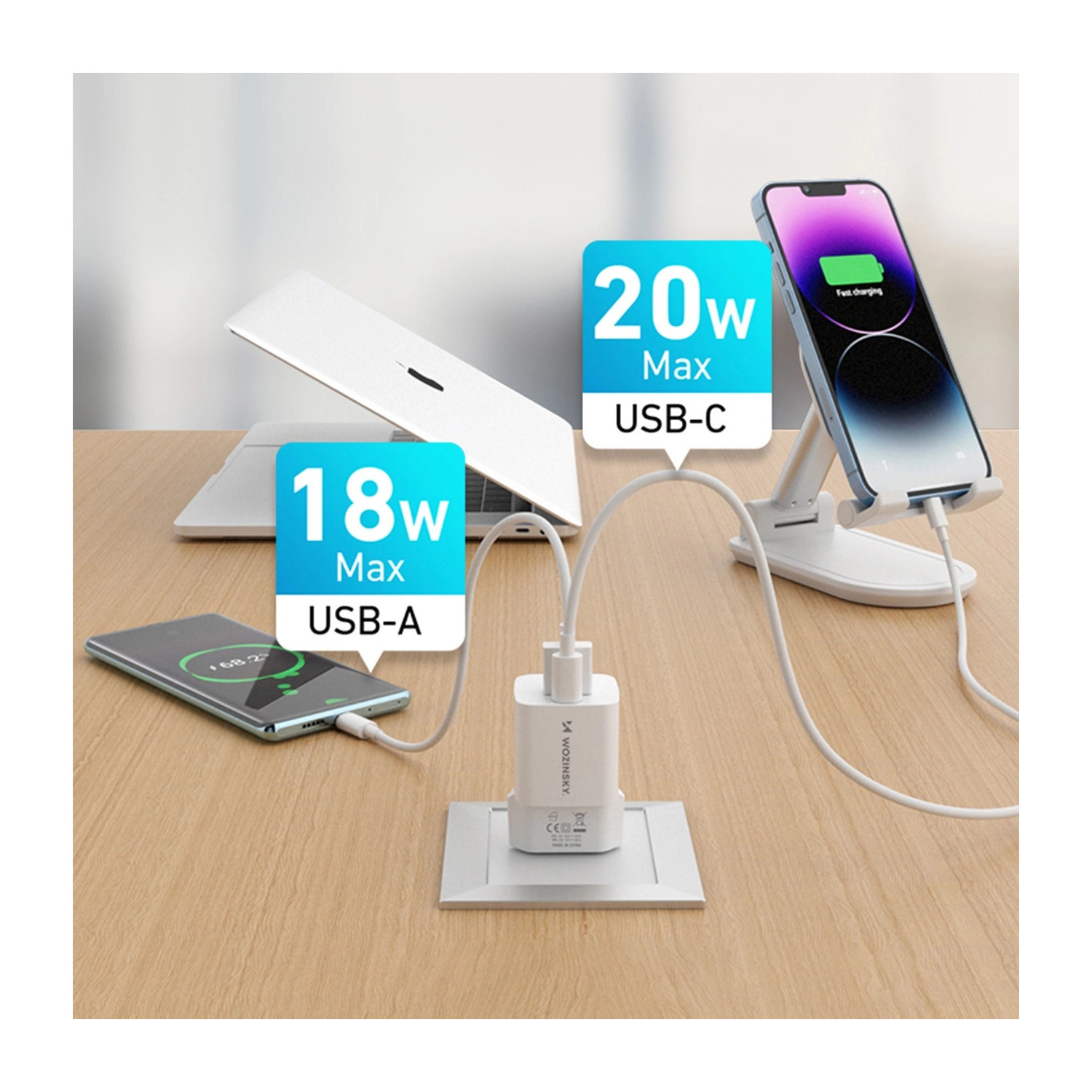 Ładowanie urządzeń: telefon na podstawce, laptop i kolejny telefon, podłączone do ładowarki Wozinsky.