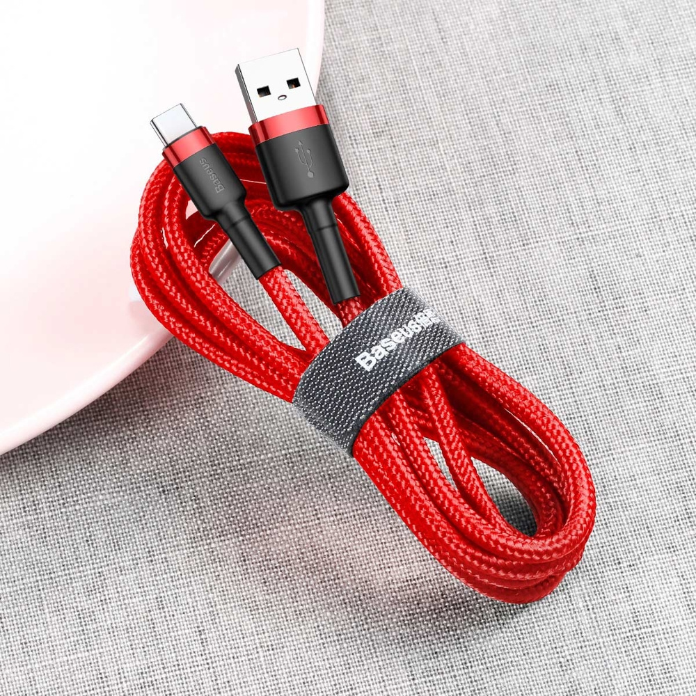 Rode en zwarte USB-naar-USB-C-kabel met riem op een gestructureerd oppervlak.