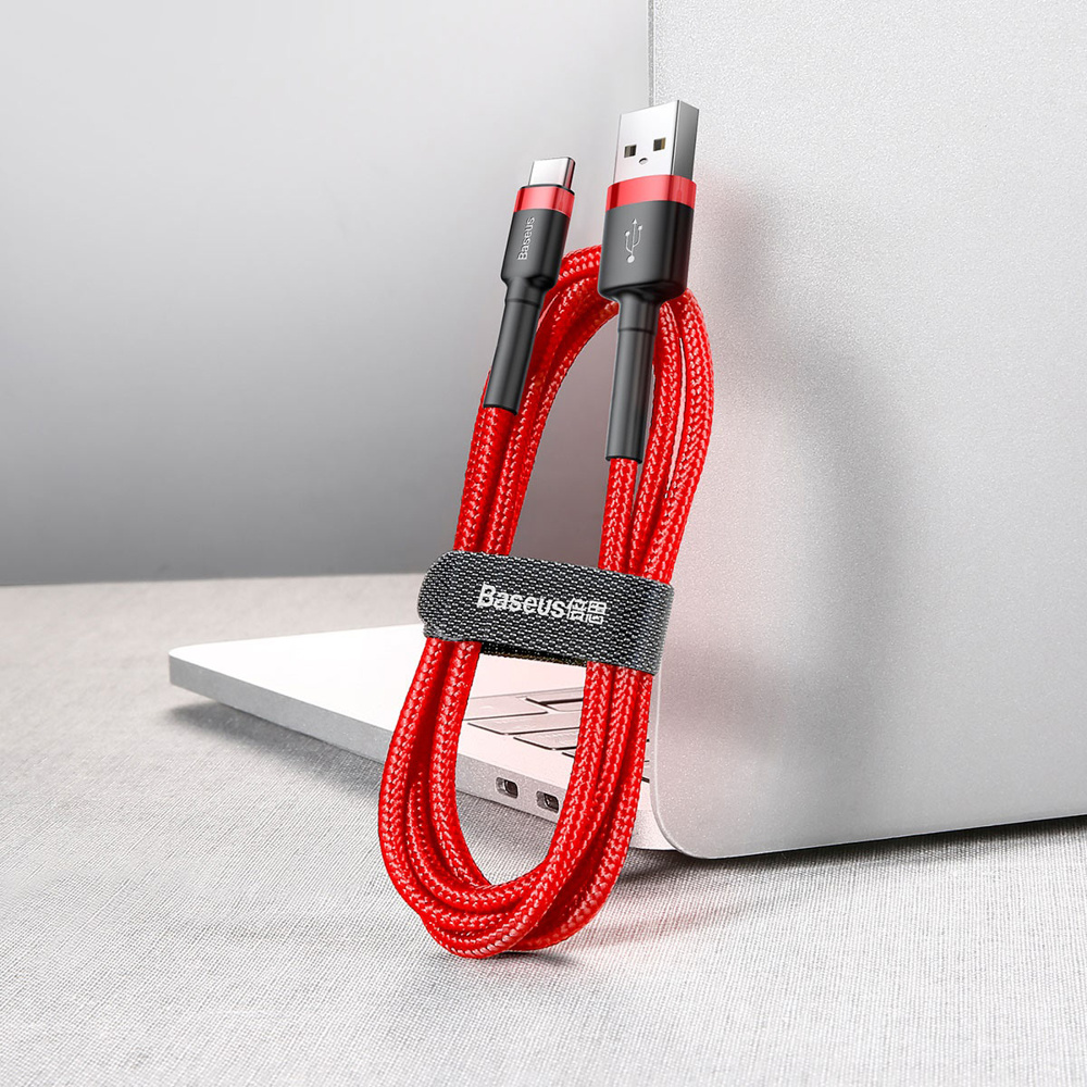 Rode en zwarte USB-naar-USB-C-kabel met riem leunend op een laptop.