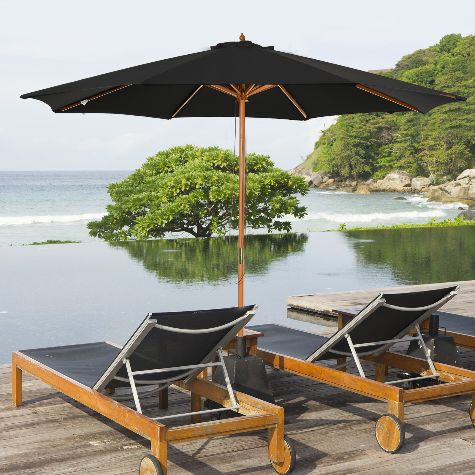 Área de descanso al aire libre con sombrilla negra sobre sillones, con vista a una piscina y al océano.