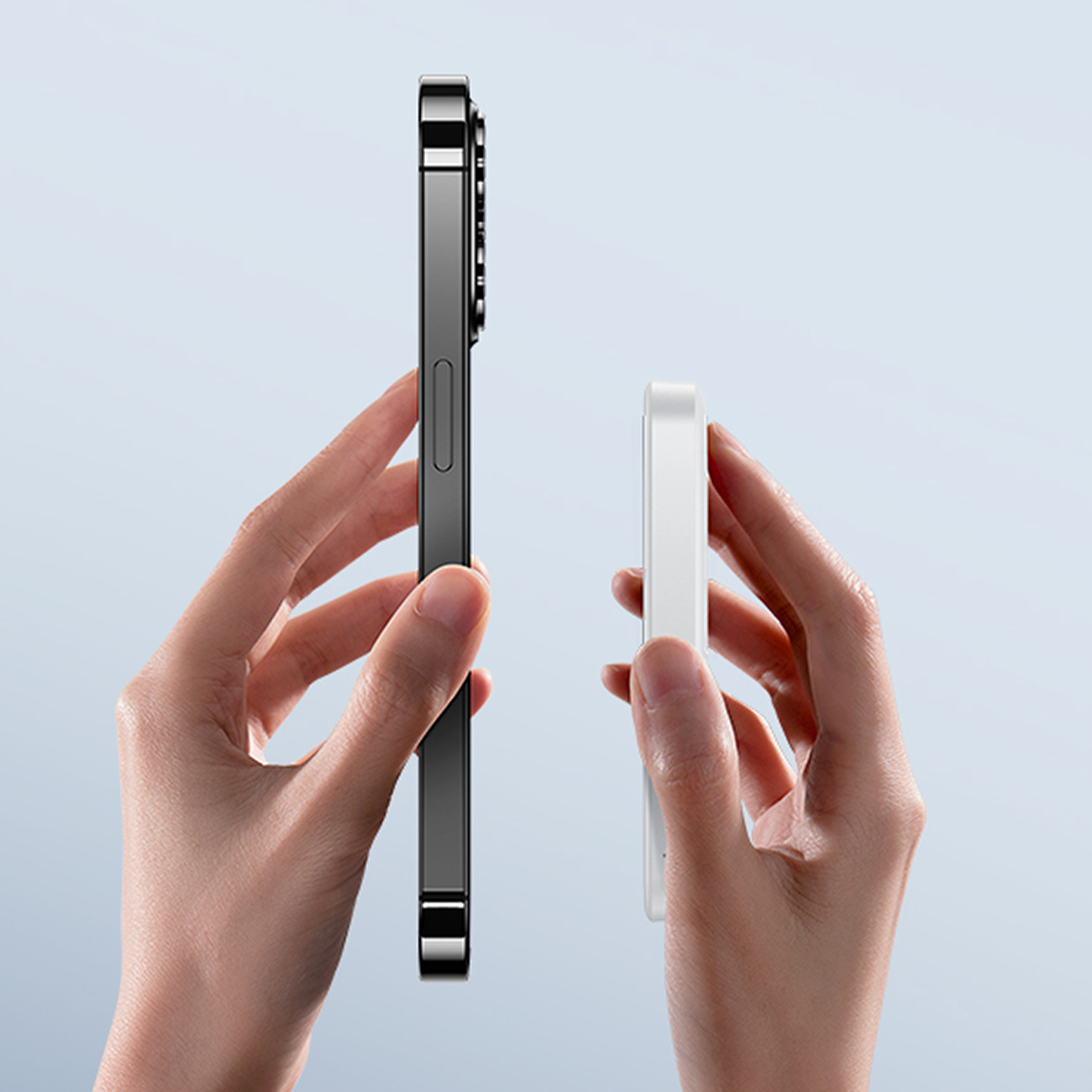 Ręka trzyma telefon obok power banku Baseus, pokazując porównanie rozmiarów.