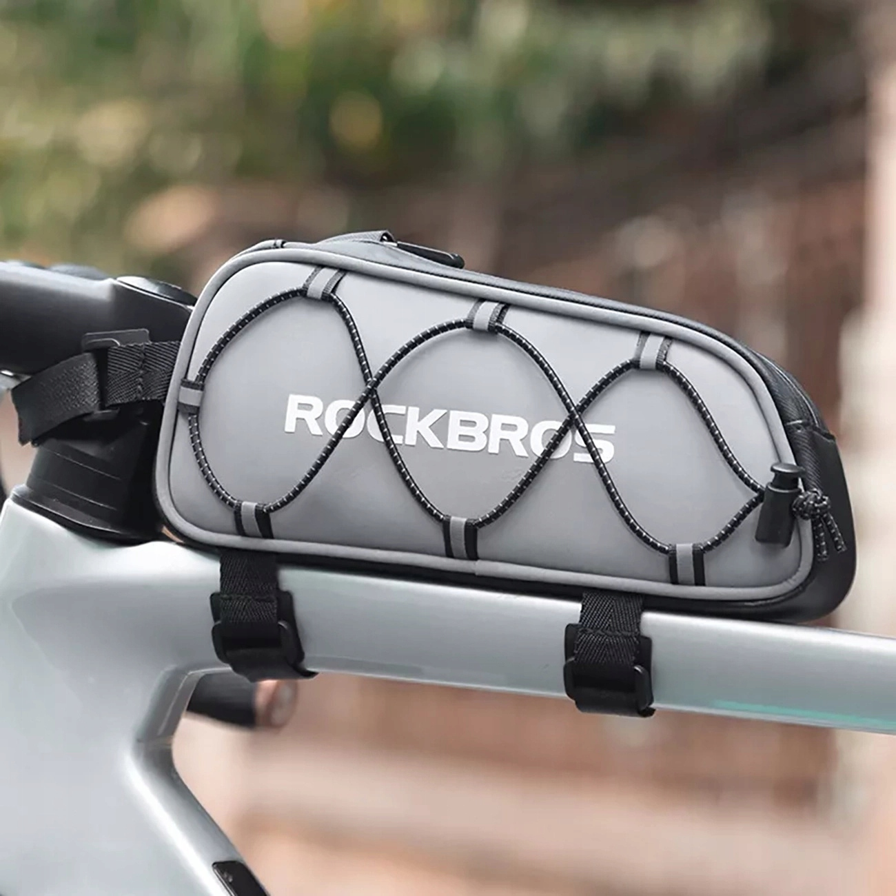 Szara torba rowerowa ROCKBROS z czarnymi paskami przymocowanymi do ramy roweru. Ma czarną gumkę.