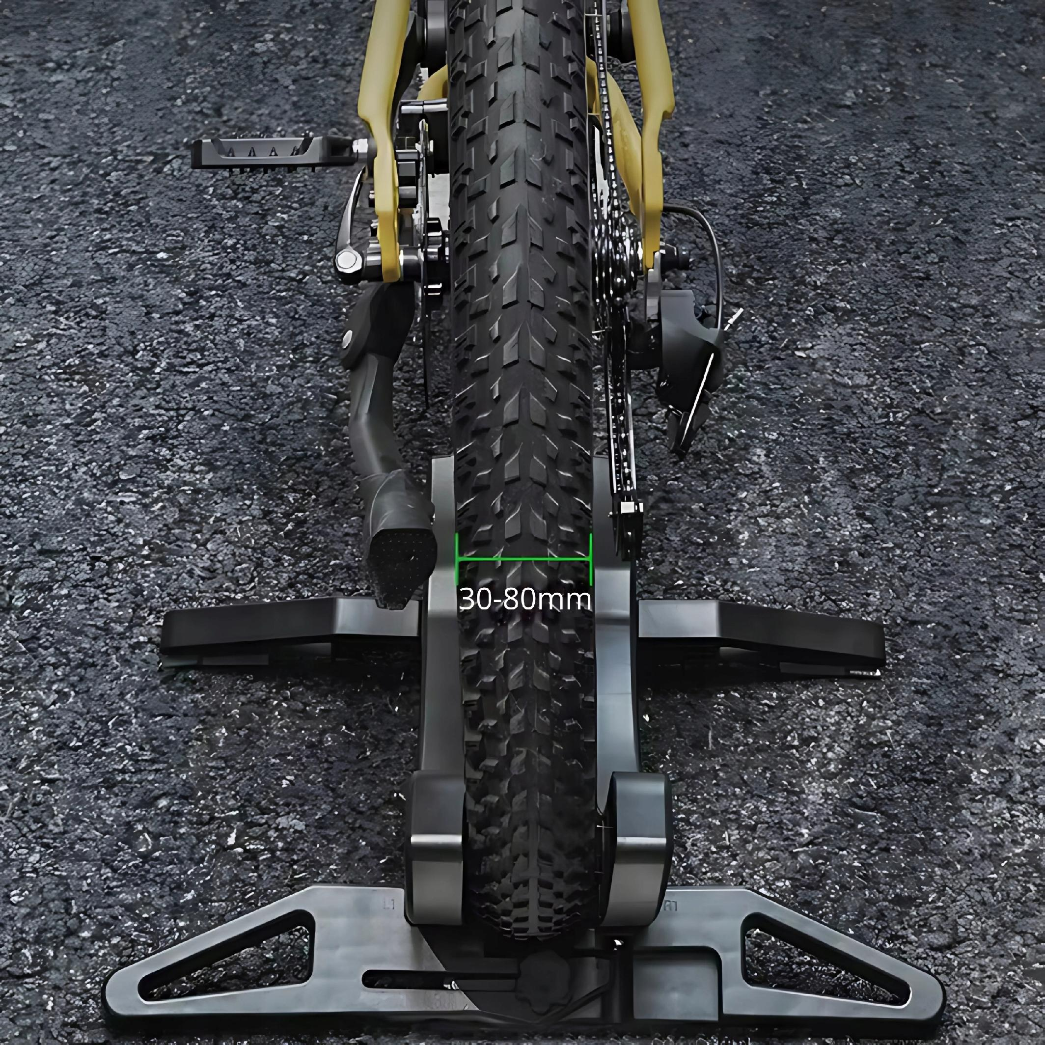 Opona rowerowa na czarnym stojaku. Opona jest gruba i ma bieżnik, a stojak jest regulowany.