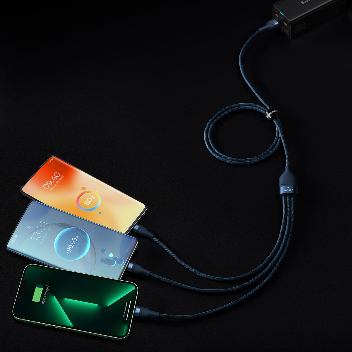 Trois téléphones sont en charge avec un câble noir multiconnecteur sur une surface noire.