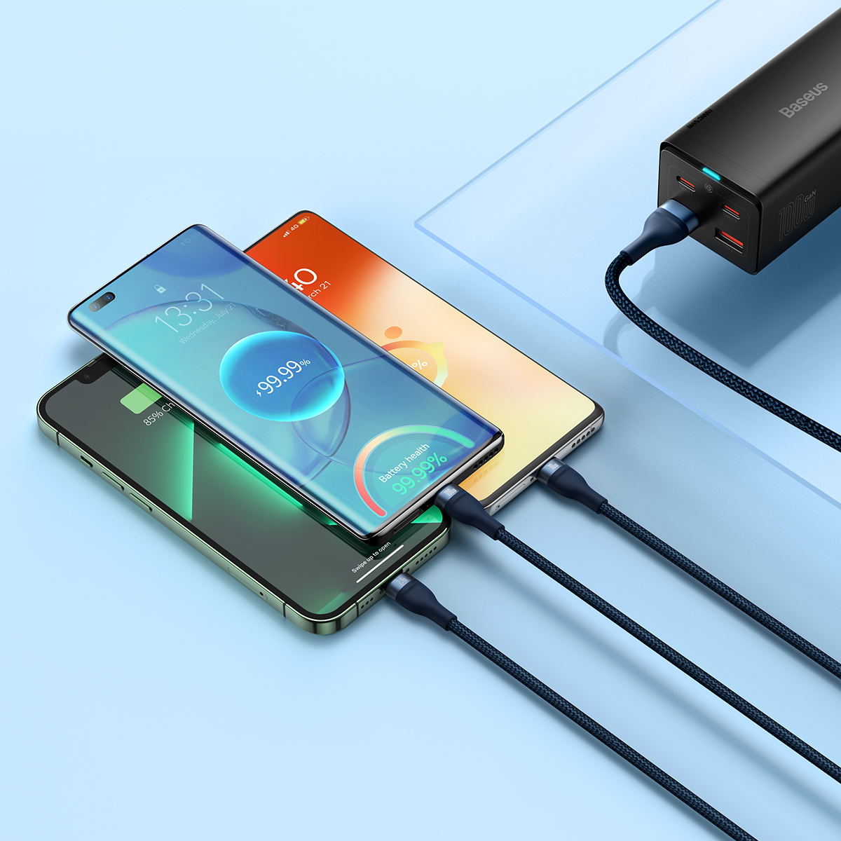 Trois téléphones en charge avec des câbles noirs et un bloc de charge Baseus sur une surface bleue.