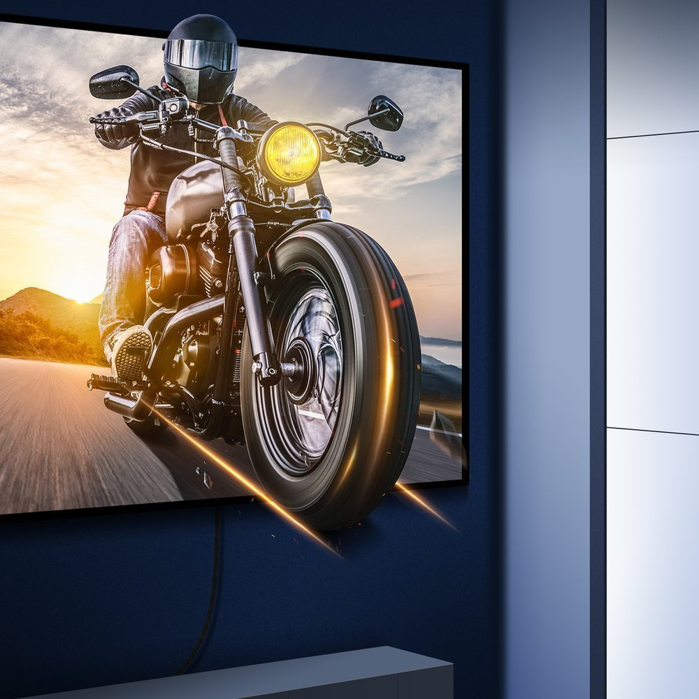 Motocykl na ekranie telewizora z podłączonym kablem Baseus, zamontowany na niebieskiej ścianie.