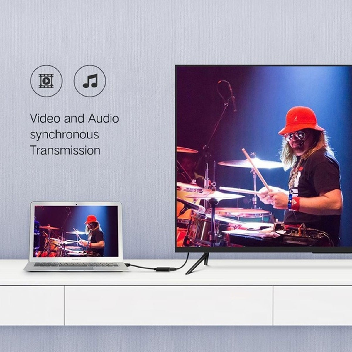 Laptop i telewizor pokazują grającego na perkusji perkusistę, połączone kablem UGREEN do przesyłania wideo/audio.