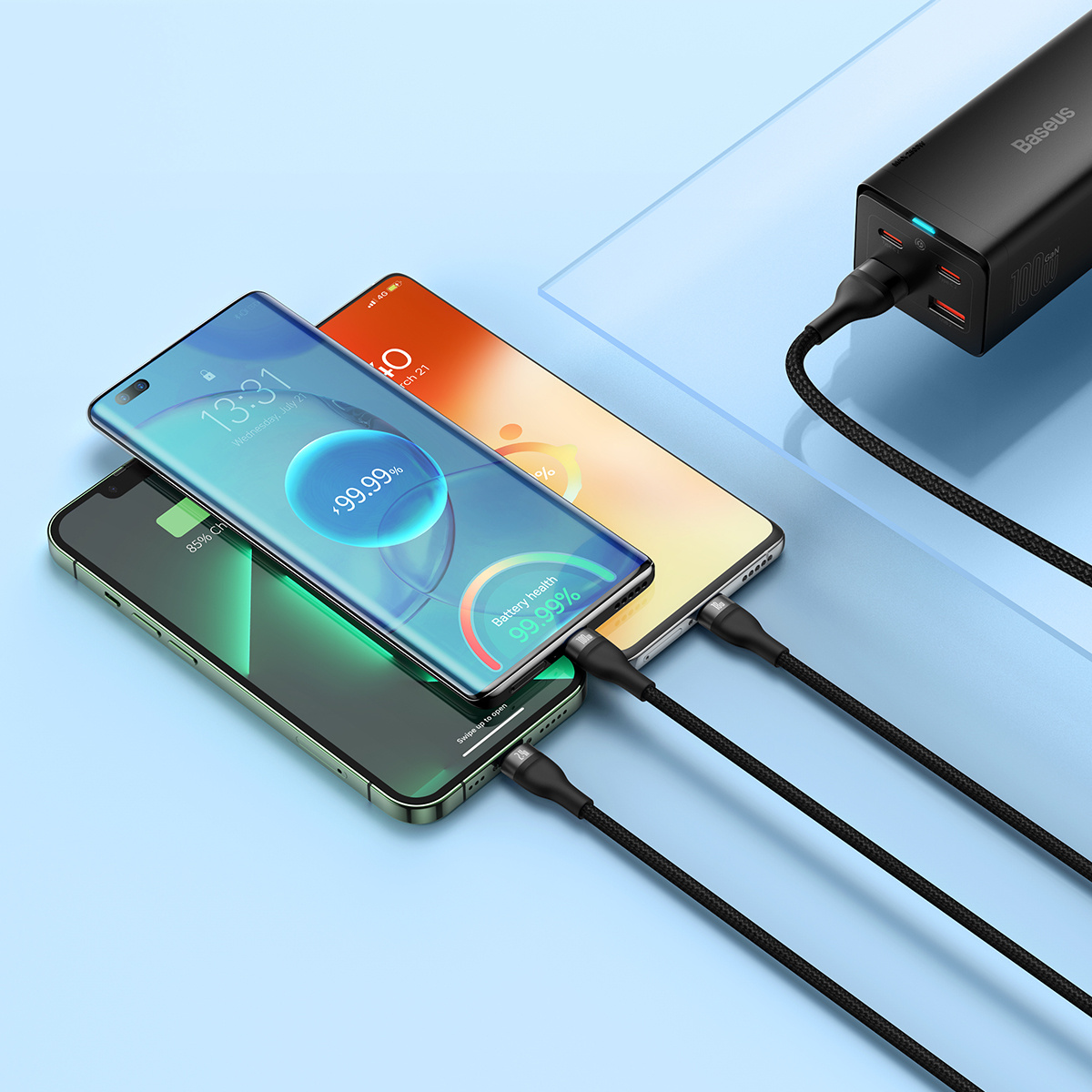 Tre smartphone si caricano su una superficie azzurra. Collegati tramite un cavo multi-connettore a un caricabatterie Baseus.