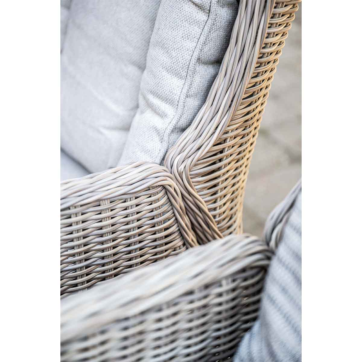 Gros plan d'une chaise en osier grise avec un coussin gris, montrant la texture et le design du meuble.