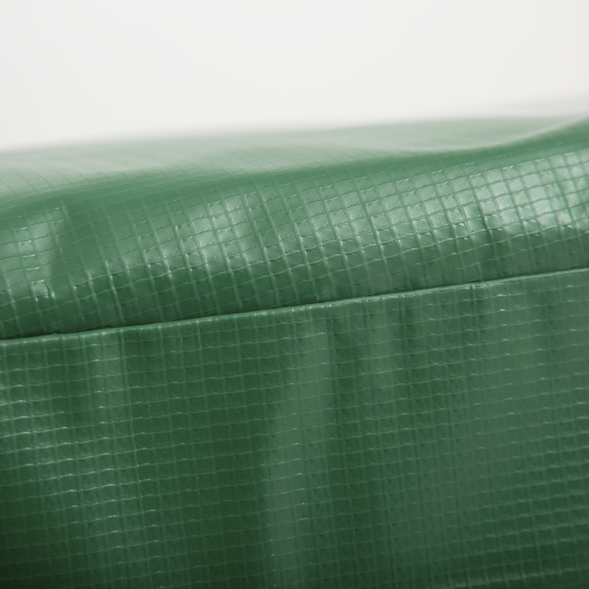 La imagen muestra un primer plano de un material verde texturizado, posiblemente un tejido duradero y resistente a la intemperie.