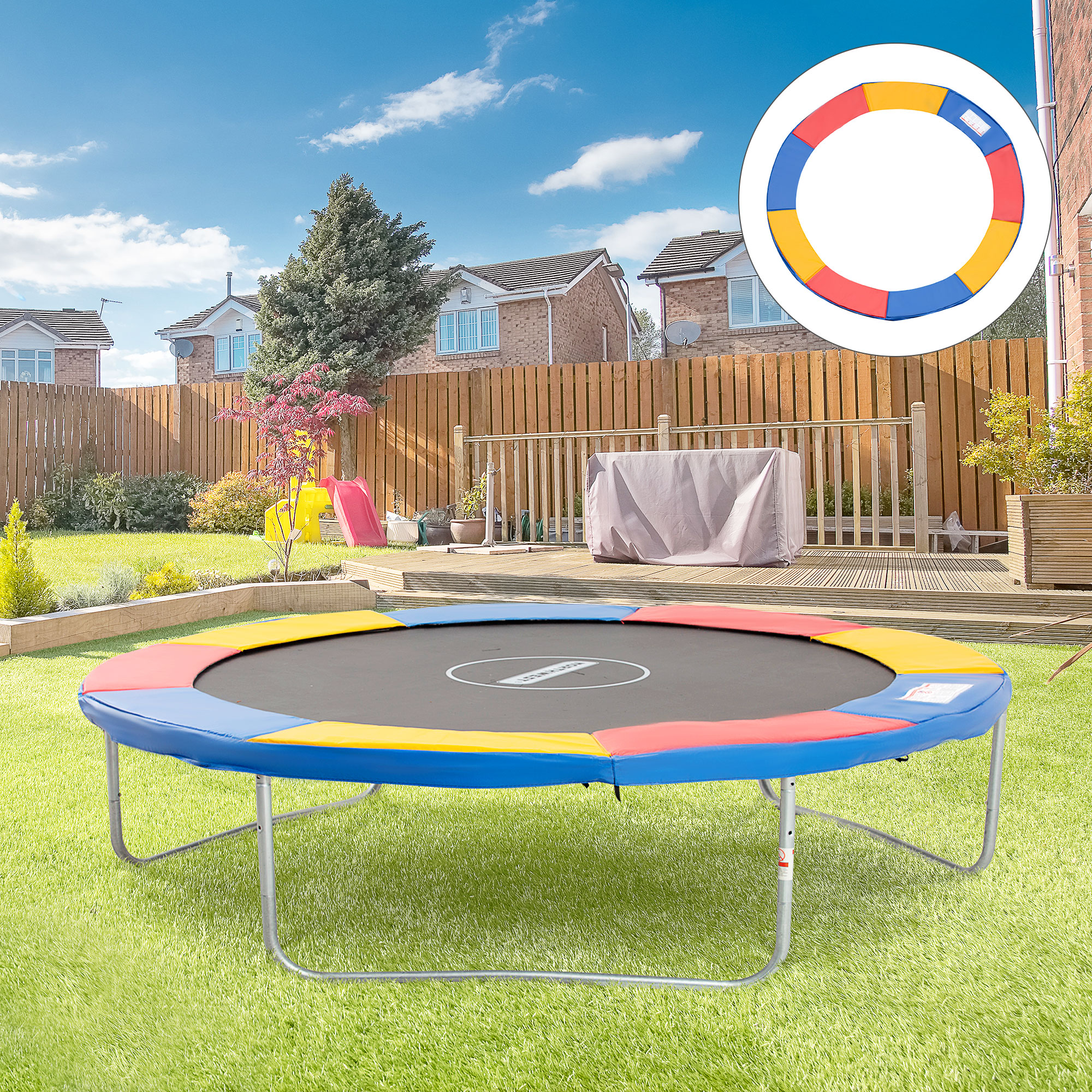 Un trampolín colorido se encuentra sobre césped verde en un patio trasero con una cerca de madera y cielo azul.