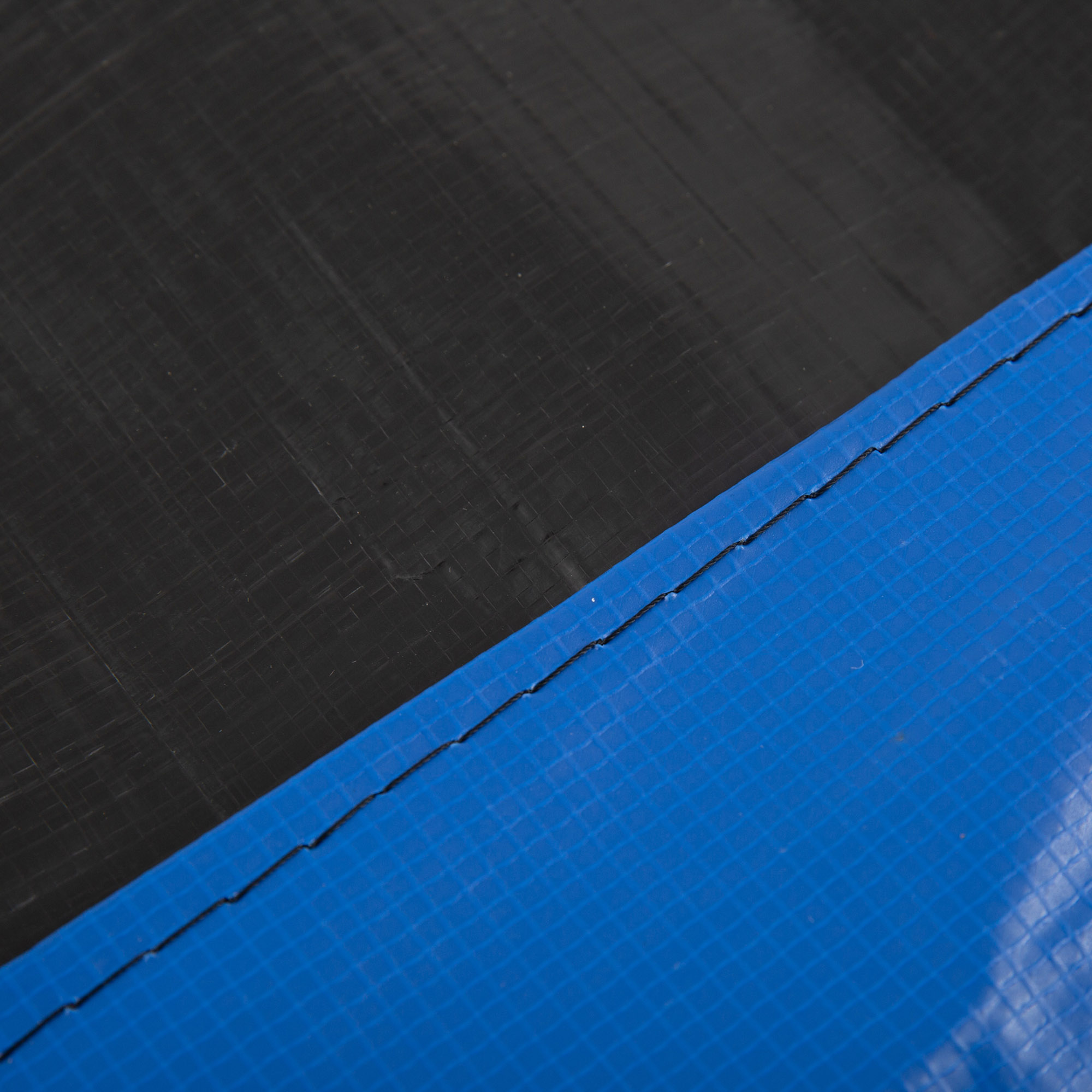 Un primer plano muestra la costura entre el material negro y azul del trampolín.