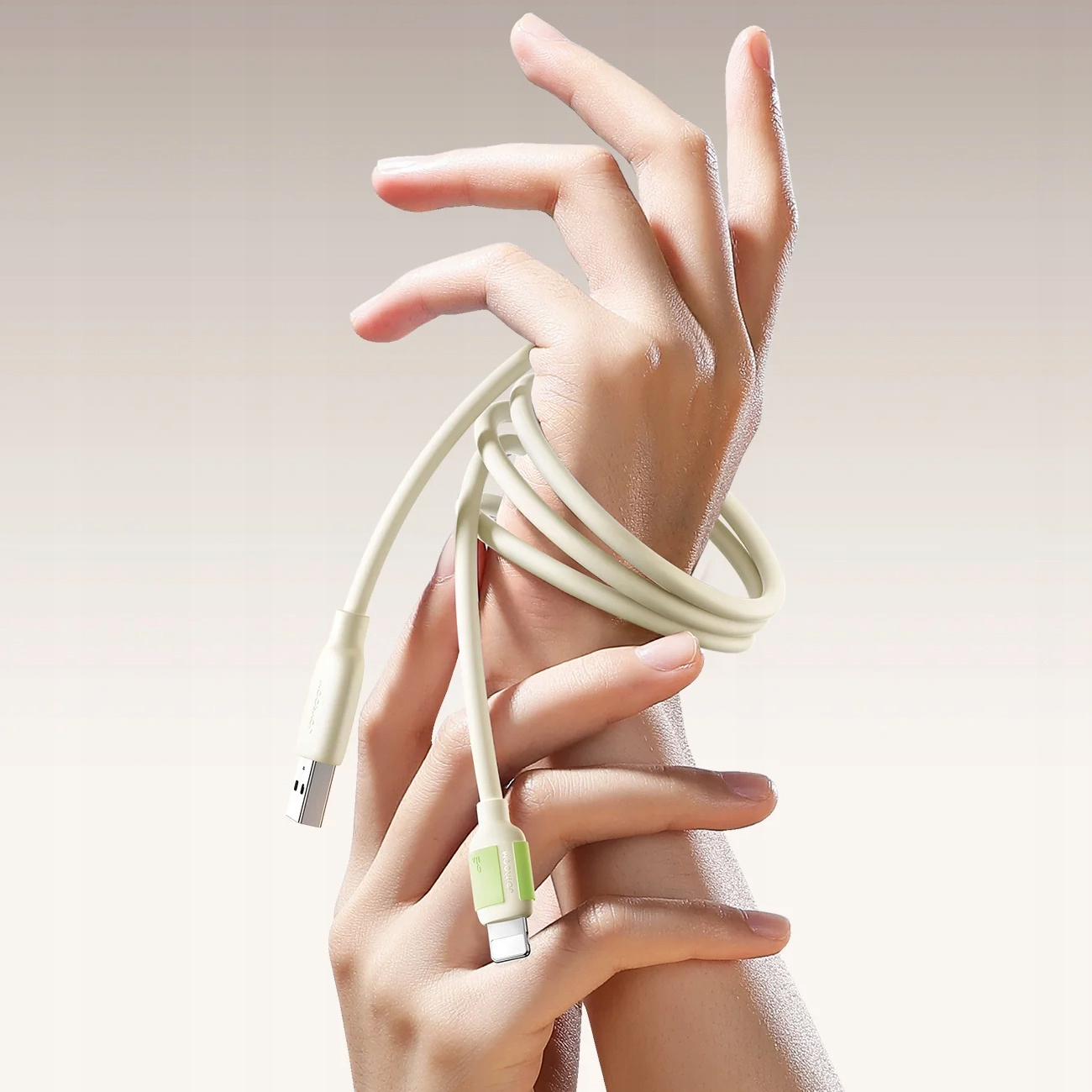 Une main tenant un câble USB blanc enroulé avec des connecteurs aux deux extrémités.