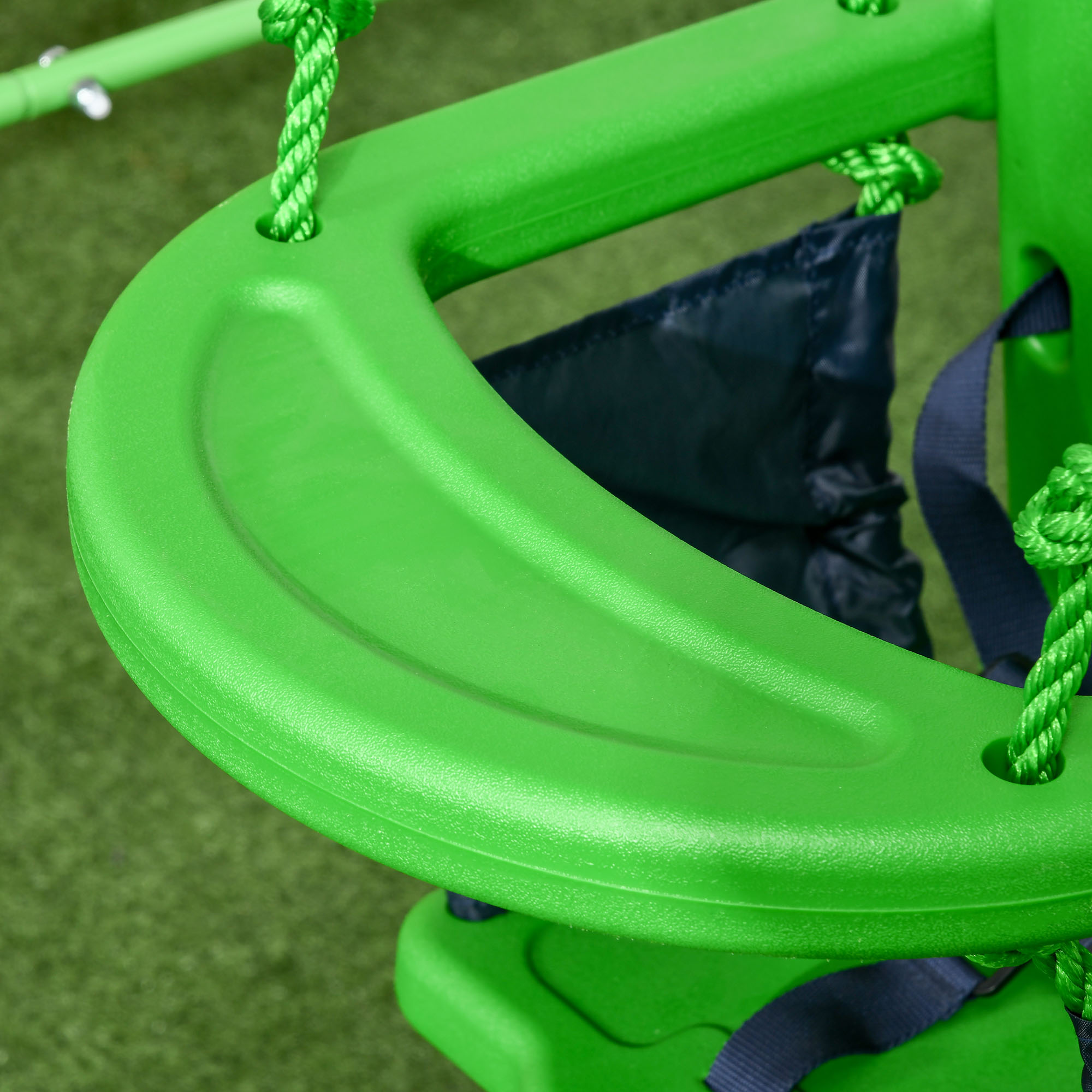 Primer plano de un asiento de columpio verde para bebés con correas de seguridad y cuerdas.