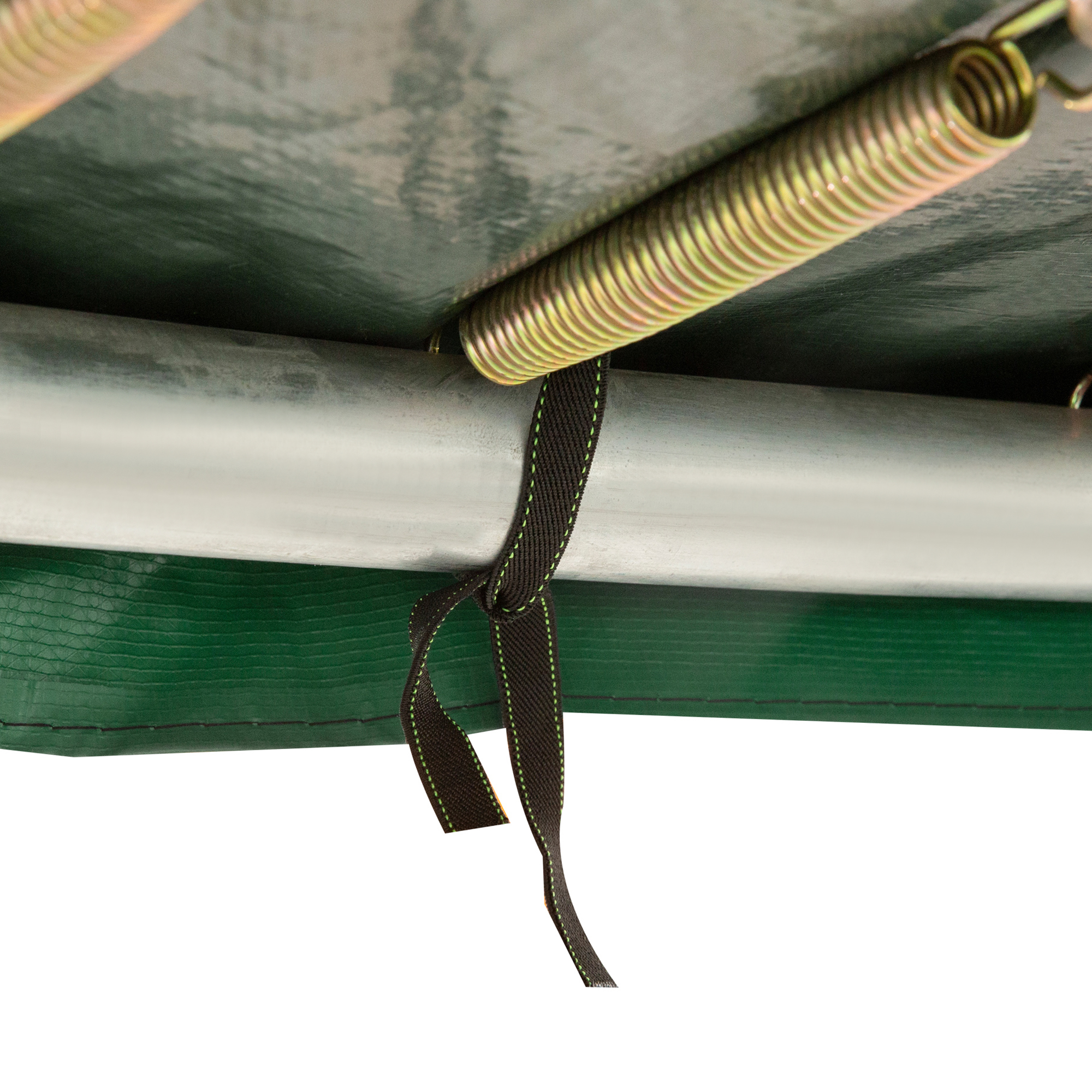 Un resorte de trampolín está sujeto a un marco con una correa negra frente a una lona verde.